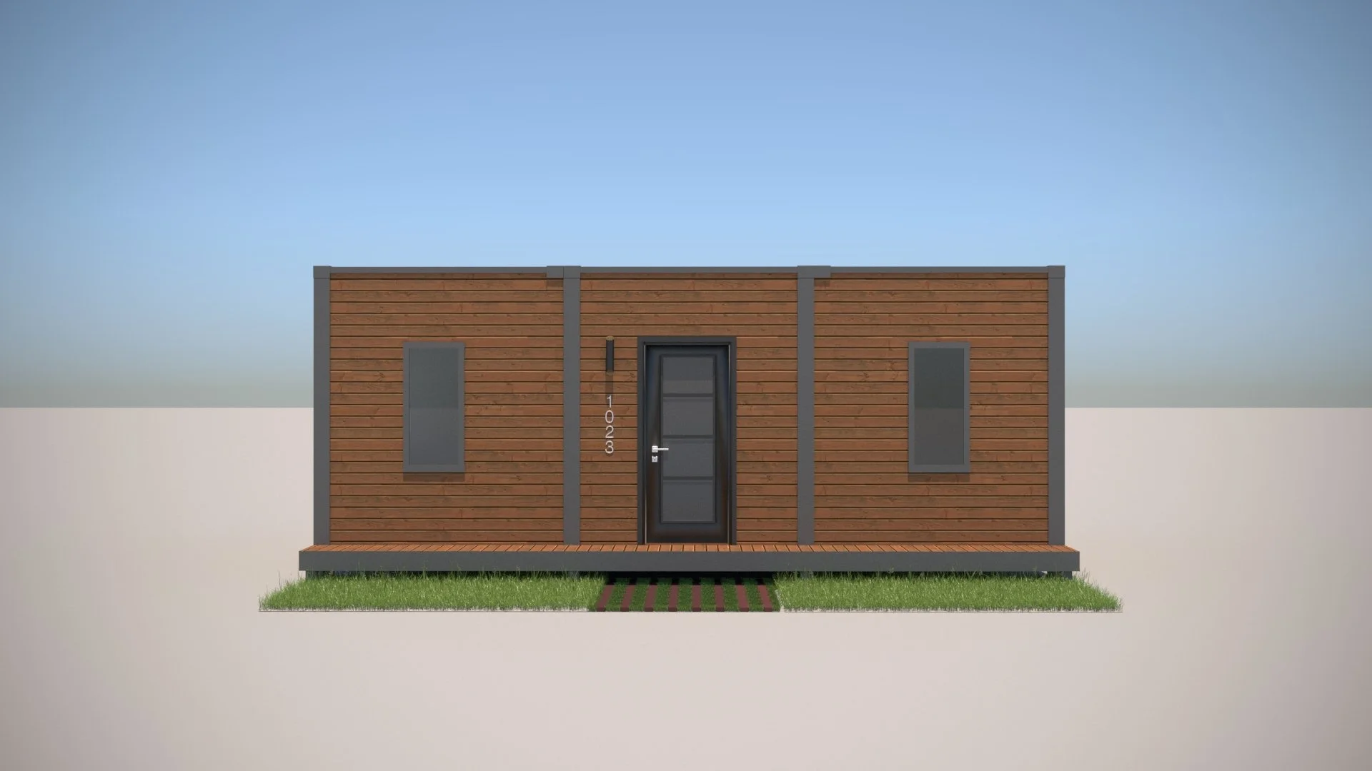 Front view of a modern tiny house with a wooden exterior, black door, and two narrow windows, on a small grassy area with a walkway, under a clear blue sky.