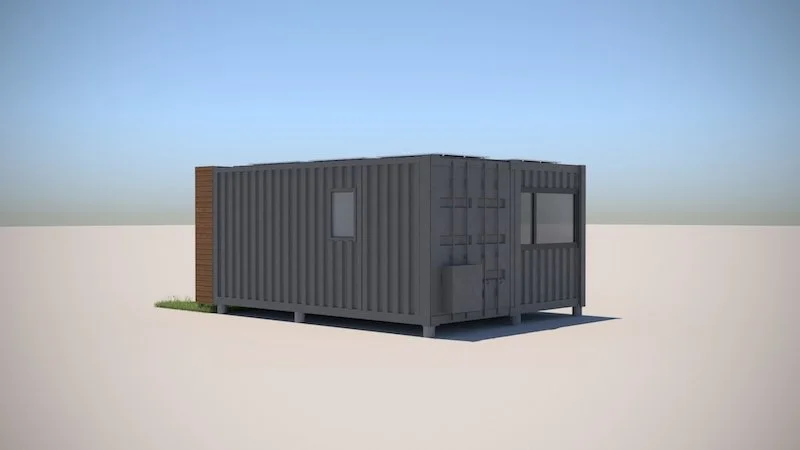 A small, rectangular, gray shipping container with two windows, door, and some hardware, set on a flat surface with a patch of grass near it, under a clear blue sky.