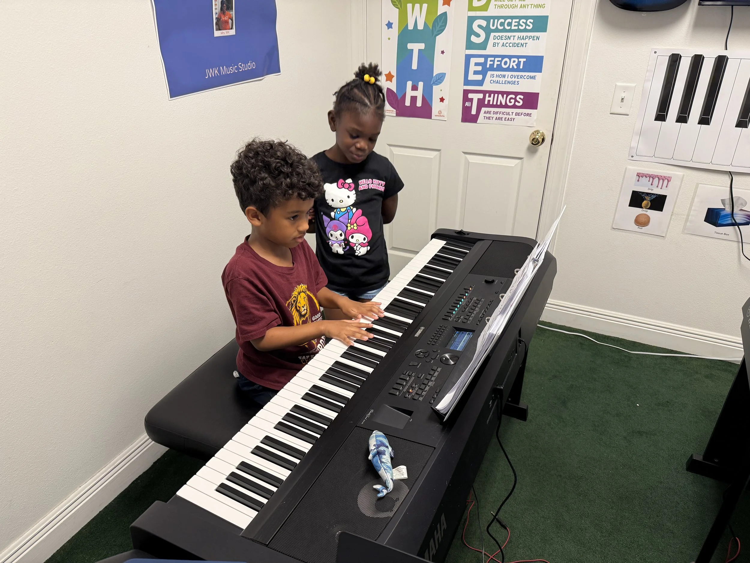 Boy sitting at piano and girl watching the boy play