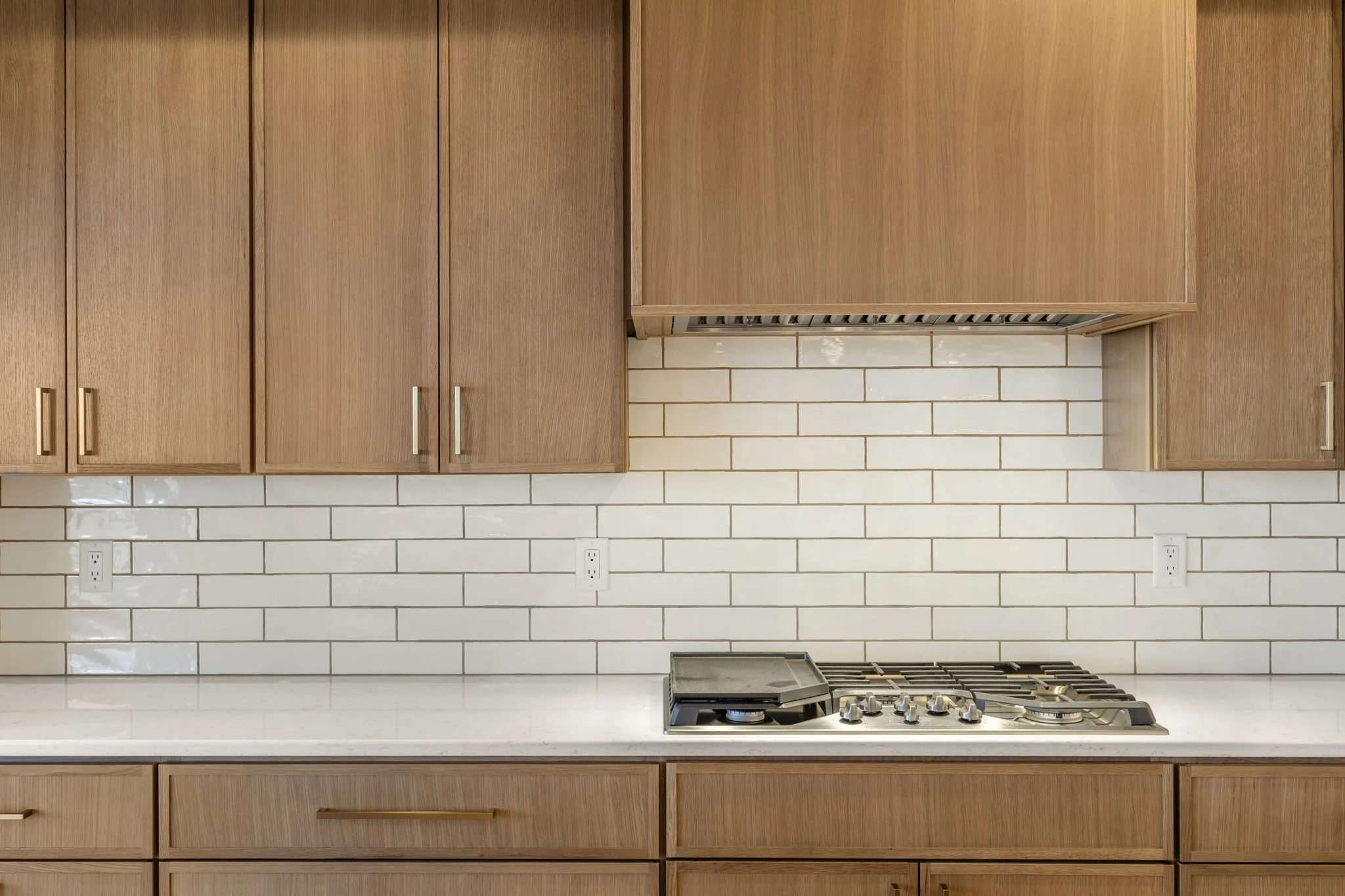 Modern kitchen with wooden cabinets, white subway tile backsplash, and a stainless steel gas stove.