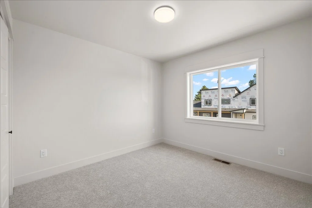 Empty white room with large window showing a house under construction outside