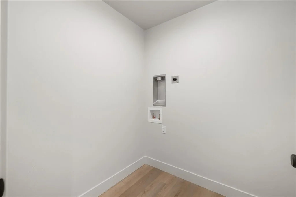 Empty laundry room with white walls, a small utility sink, and washing machine hookups.