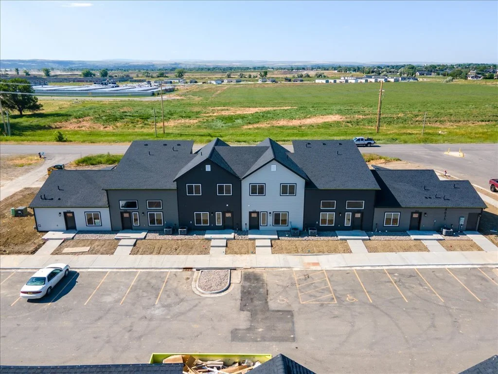 Newly constructed multi-unit residential building with parking lot and surrounding open fields