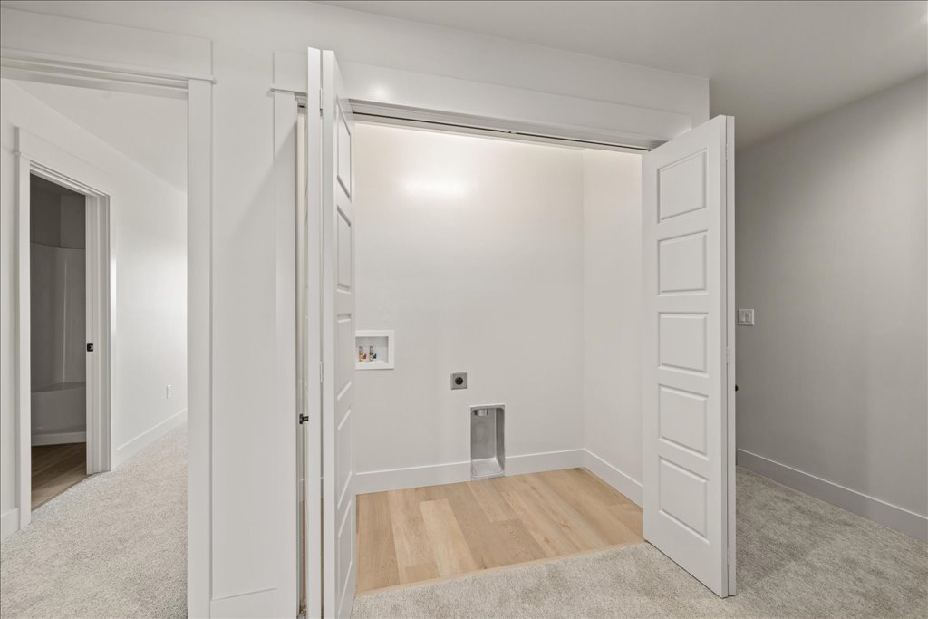 Empty laundry or utility room with white walls, open closet doors, and hookups for washer and dryer.