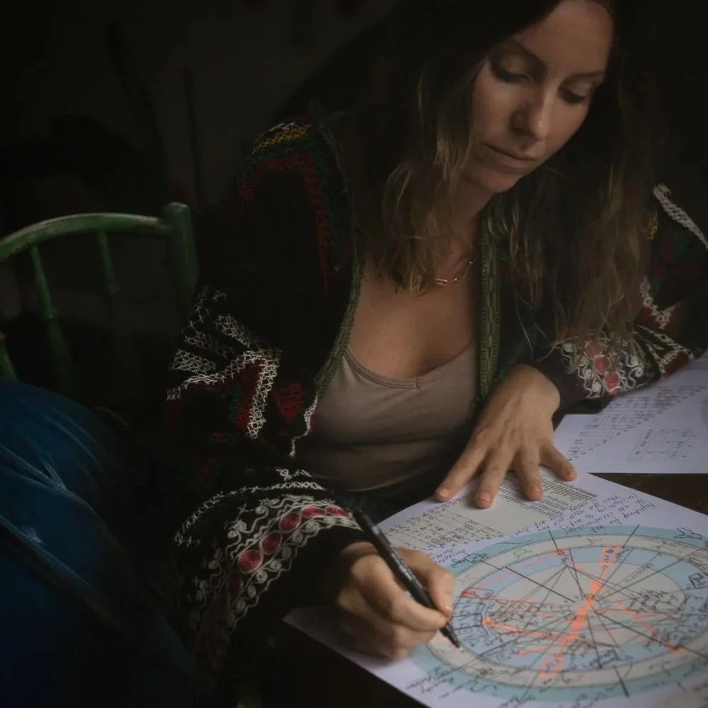 Astrologer, Megan Todd sits at desk drawing on client natal chart