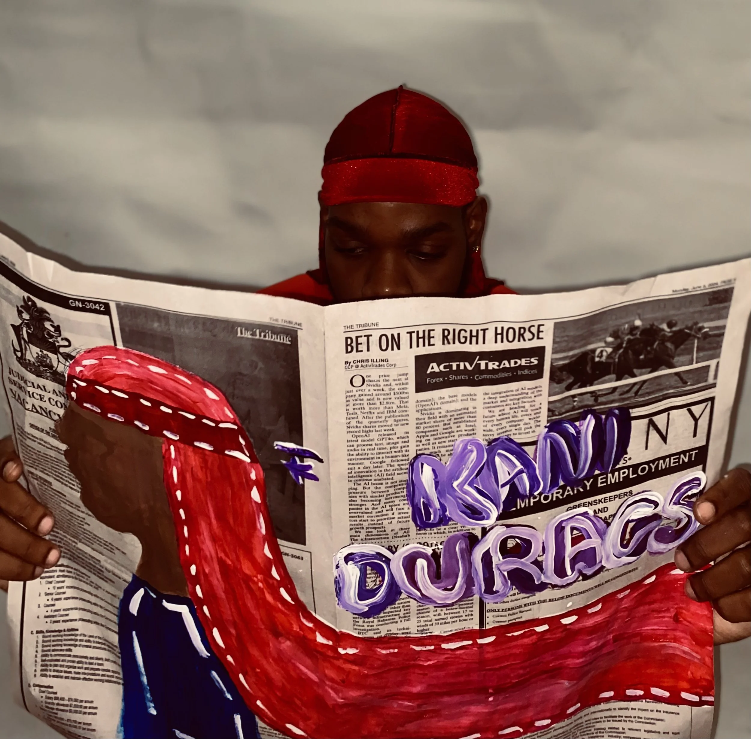 Person with a red cap reading a newspaper with an illustration of a red muscular arm and the words "DREAMS & COURAGE" painted over it.