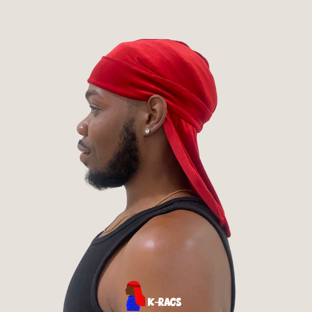 Side profile of a young man wearing a red durag, black sleeveless shirt, silver earring, and a gold chain, against a plain light background.