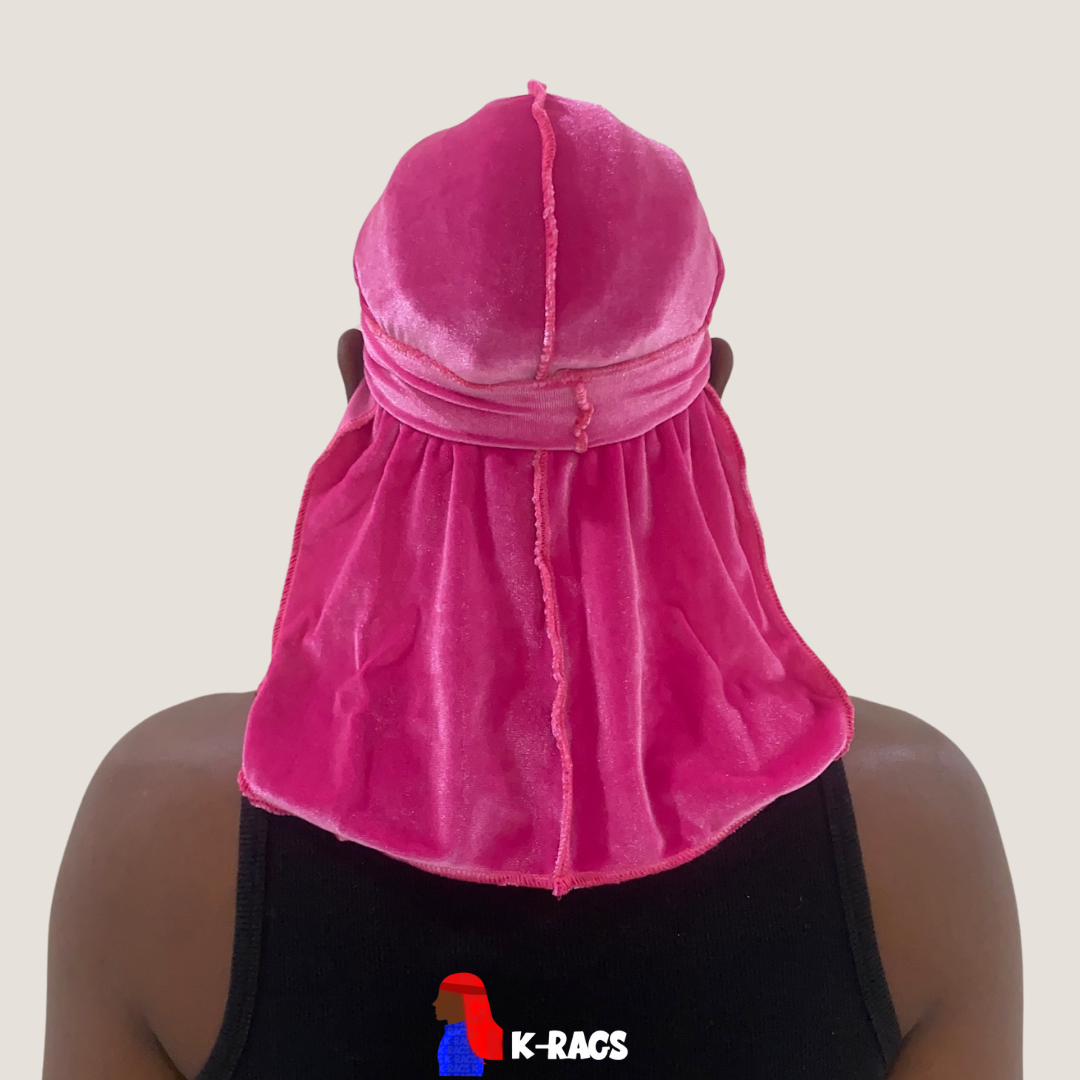 Person wearing a pink velvet durag and matching head covering viewed from behind, with a black tank top.