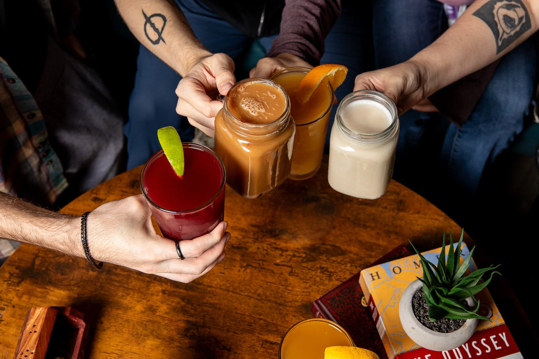 Four people clinking glass cups together. Only their hands are visible, they are doing a "cheers".