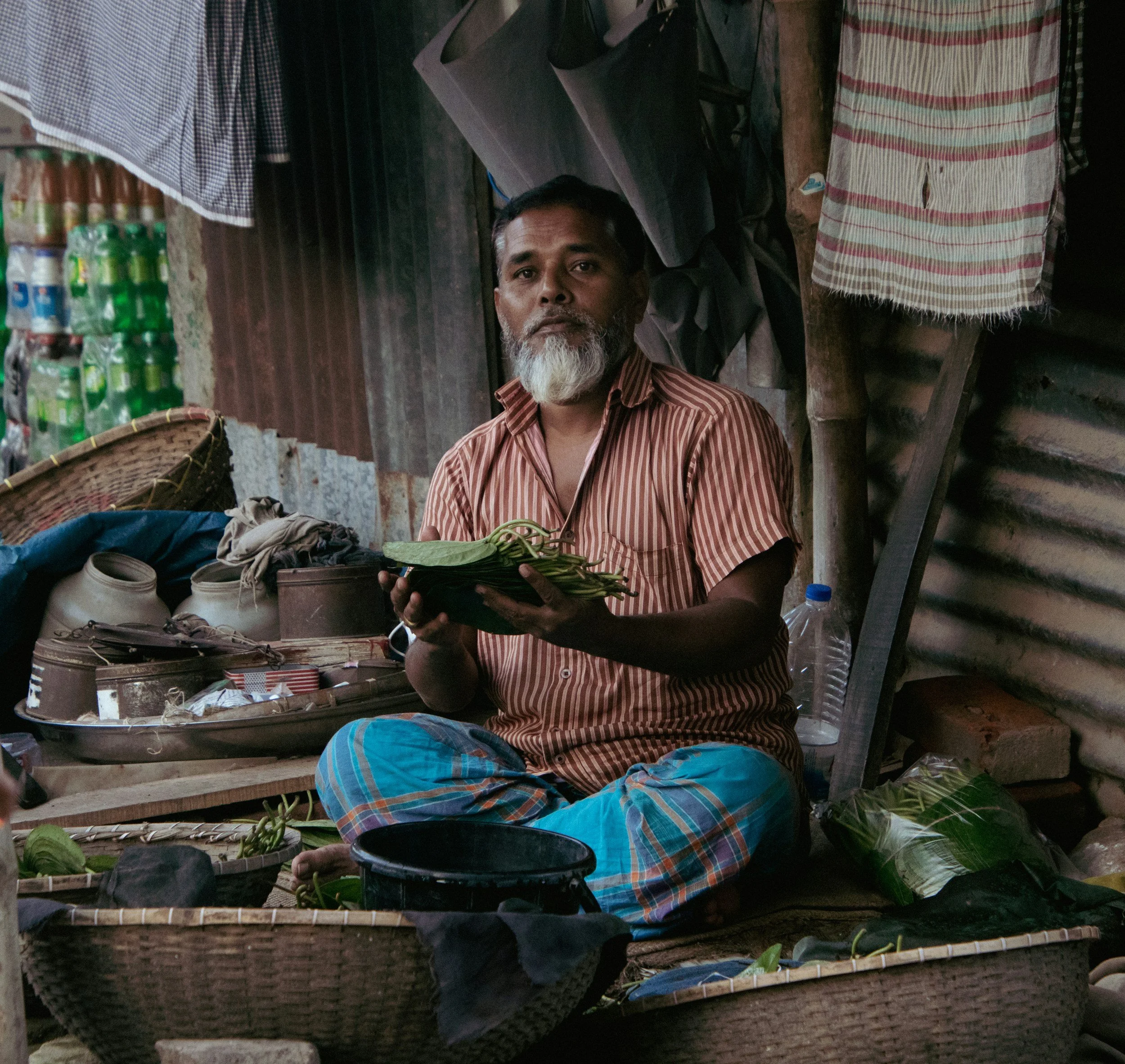 A sitting man holding a bowl of kava in both hands