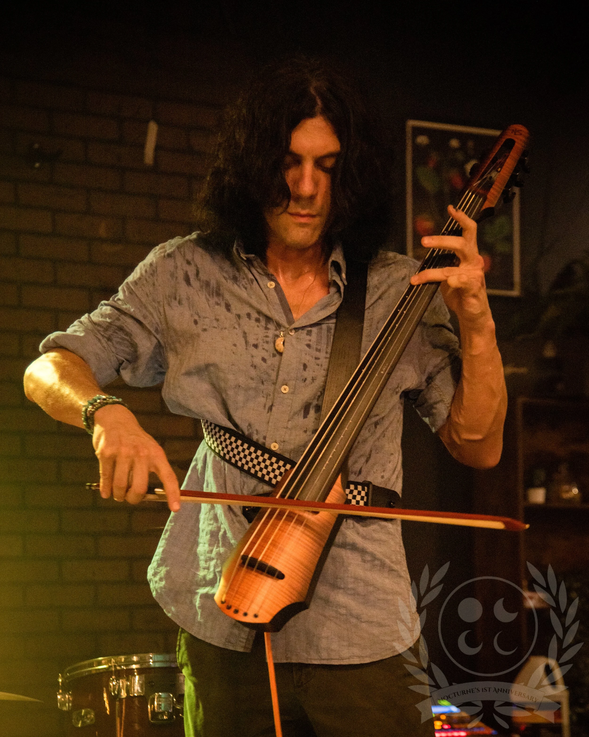 A man standing and playing an electric cello