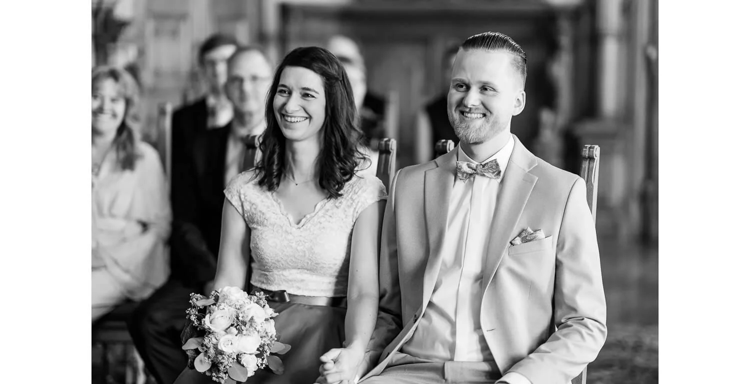 Brautpaar während der standesamtlichen Trauung im Rathaus Kaufbeuren, sitzend im Trausaal, umgeben von Gästen.