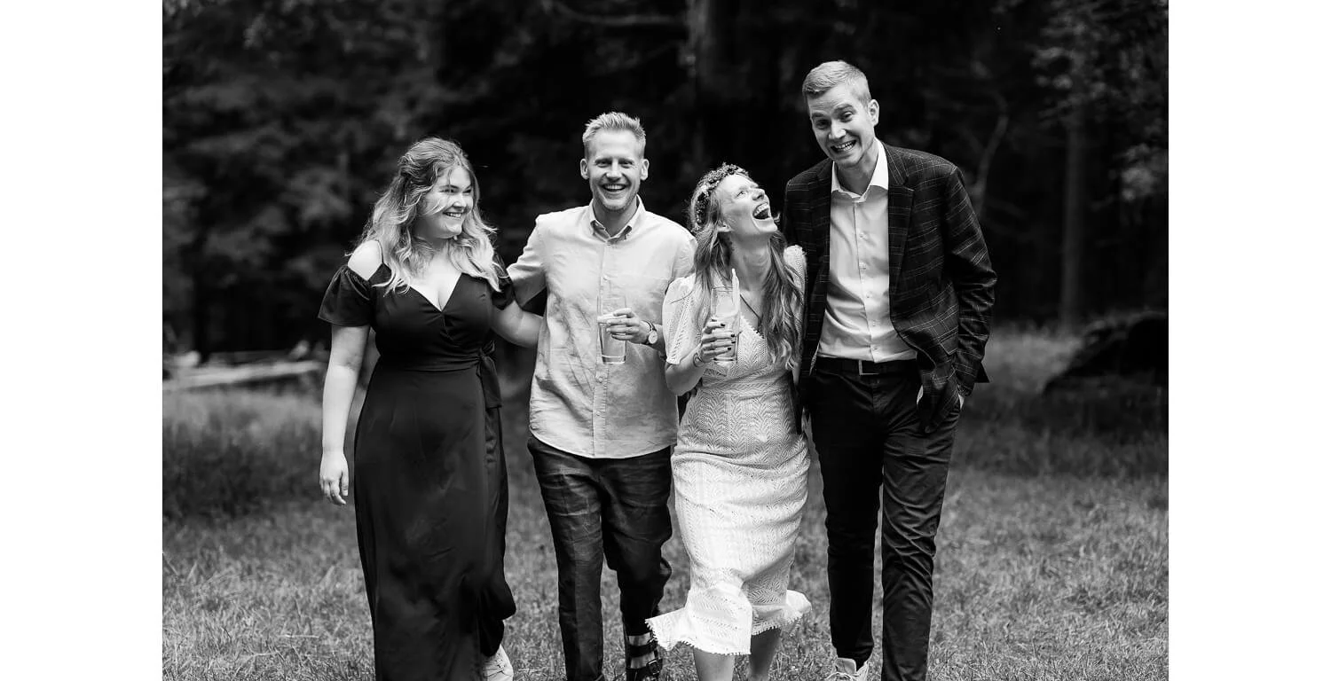 Brautpaar geht lachend mit Gästen nach der freien Trauung durch den Wald in Grainau