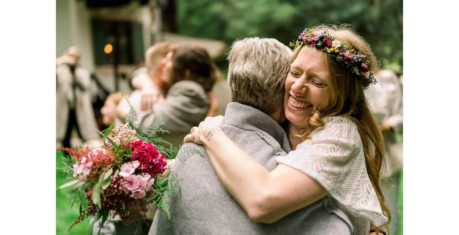 Gratulationen nach der freien Trauung im Wald in Grainau, Umarmung mit Blumenstrauß