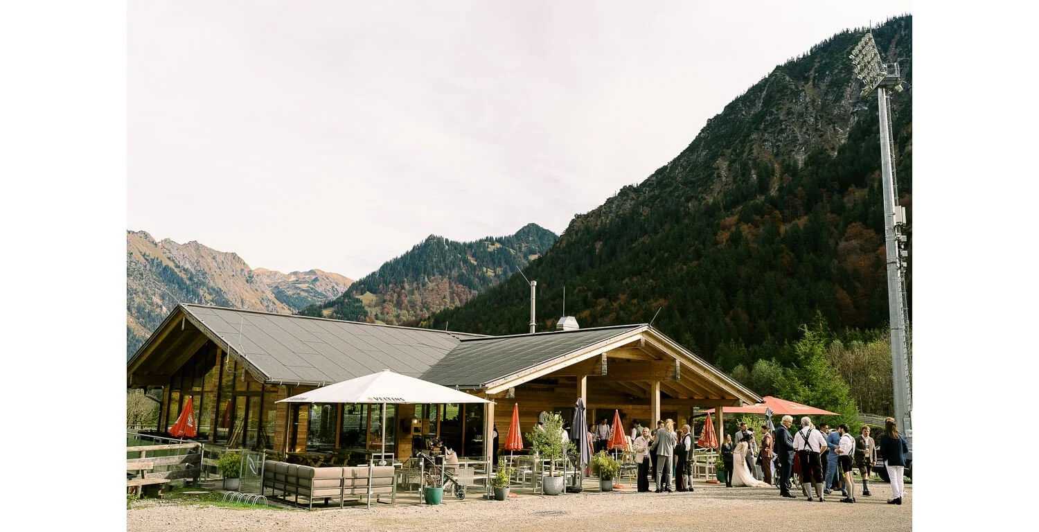 Hochzeitsgesellschaft vor der Hochzeitslocation Schanzenwirt in Oberstdorf, umgeben von den Bergen