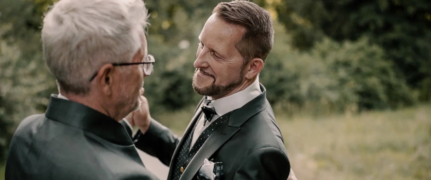 Zwei Männer stehen sich nah gegenüber und blicken sich lächelnd an, aufgenommen während ihrer gleichgeschlechtlichen Hochzeit in Füssen.