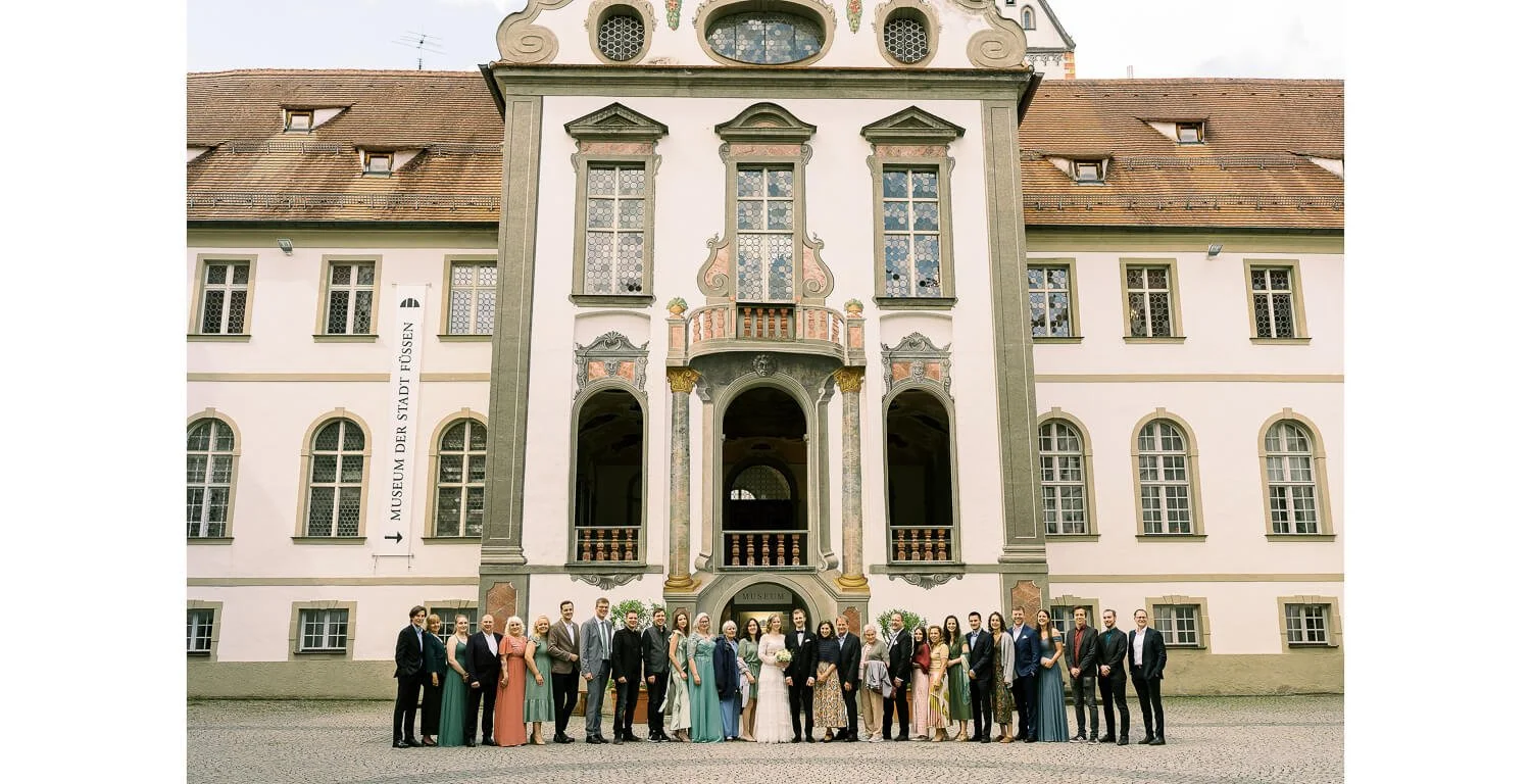Gruppenfoto der Hochzeitsgesellschaft vor dem Kloster St. Mang nach der standesamtlichen Trauung in Füssen