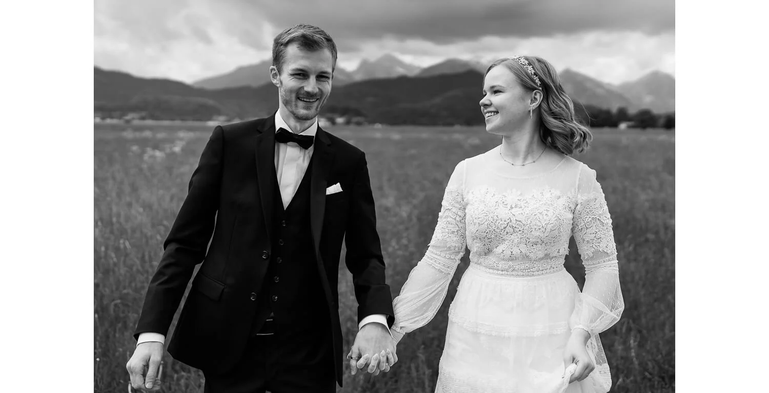 Paarshooting nach der standesamtlichen Hochzeit in Füssen, Brautpaar auf einer Wiese mit Bergkulisse im Hintergrund, schwarz-weiß