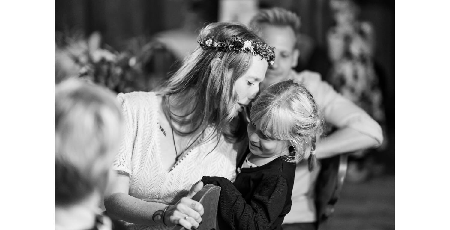 Braut küsst ein Kind liebevoll während der Hochzeitsfeier im Ferienhaus St. Hubertus in Grainau