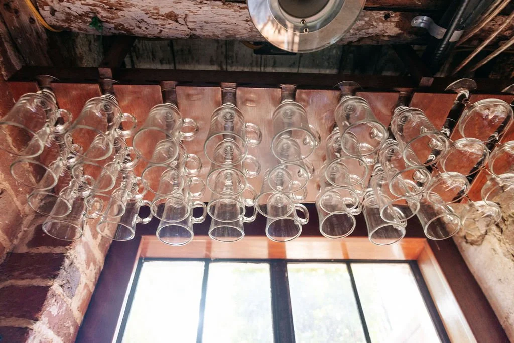 Bourbon glasses hanging from the vintage ceiling at the historic Ironclad Inn Fredericksburg Virginia tasting room