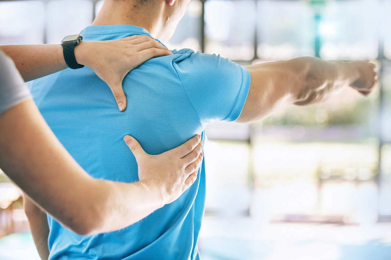 A person receiving shoulder physical therapy or assessment from a healthcare professional in a clinical setting.