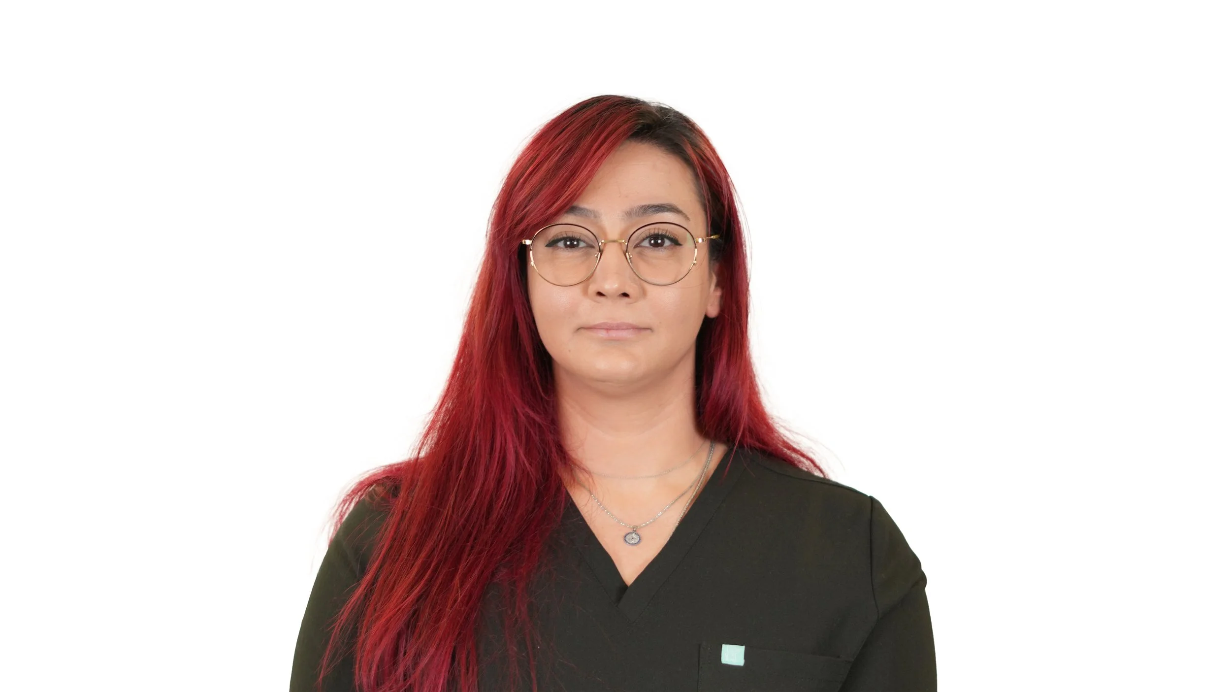 A woman with long red hair, glasses, and a black shirt standing against a plain white background.