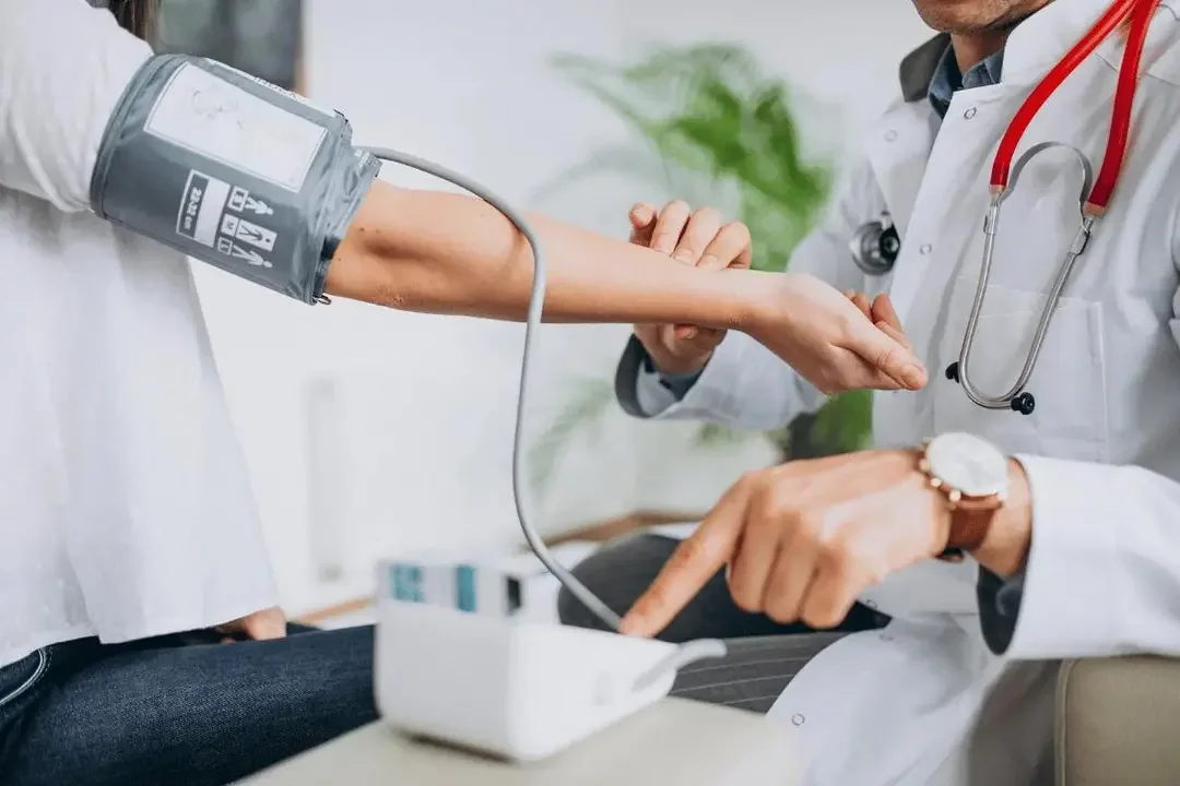 Doctor measuring patient's blood pressure using a sphygmomanometer in a clinical setting.
