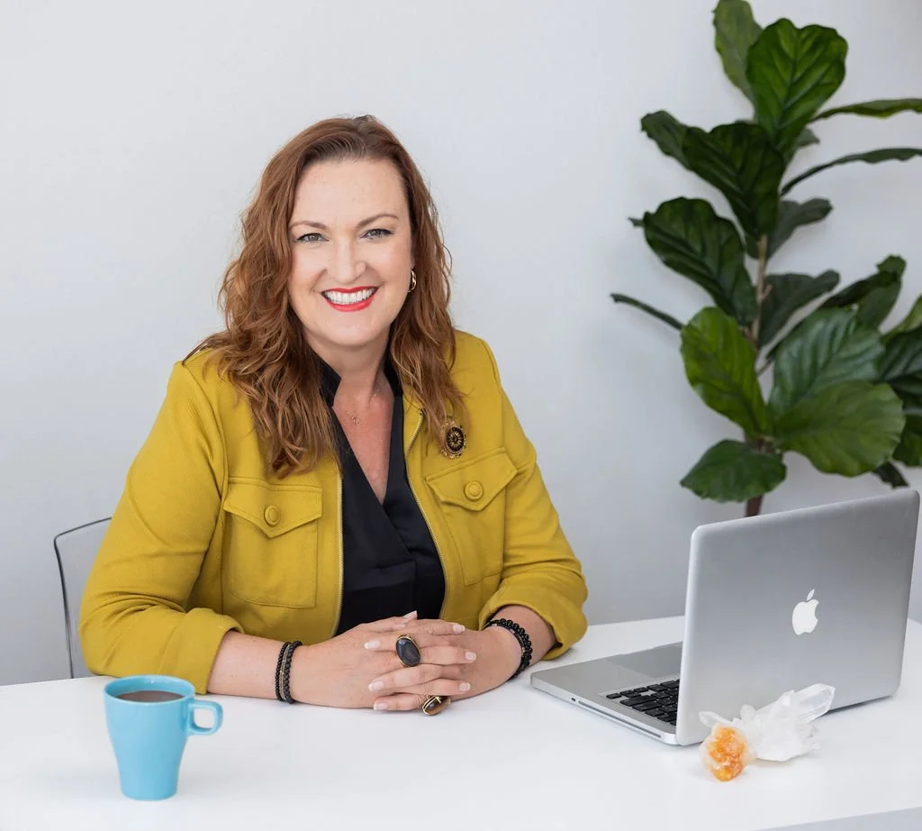Jen Hibbits, AI and strategy digital marketing consultant, smiling at desk in a bright, modern workspace.