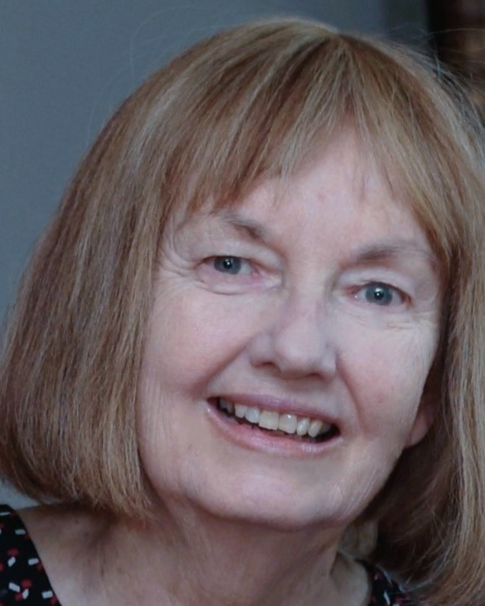Close-up of a middle-aged woman with shoulder-length reddish hair, blue eyes, and light skin, smiling.