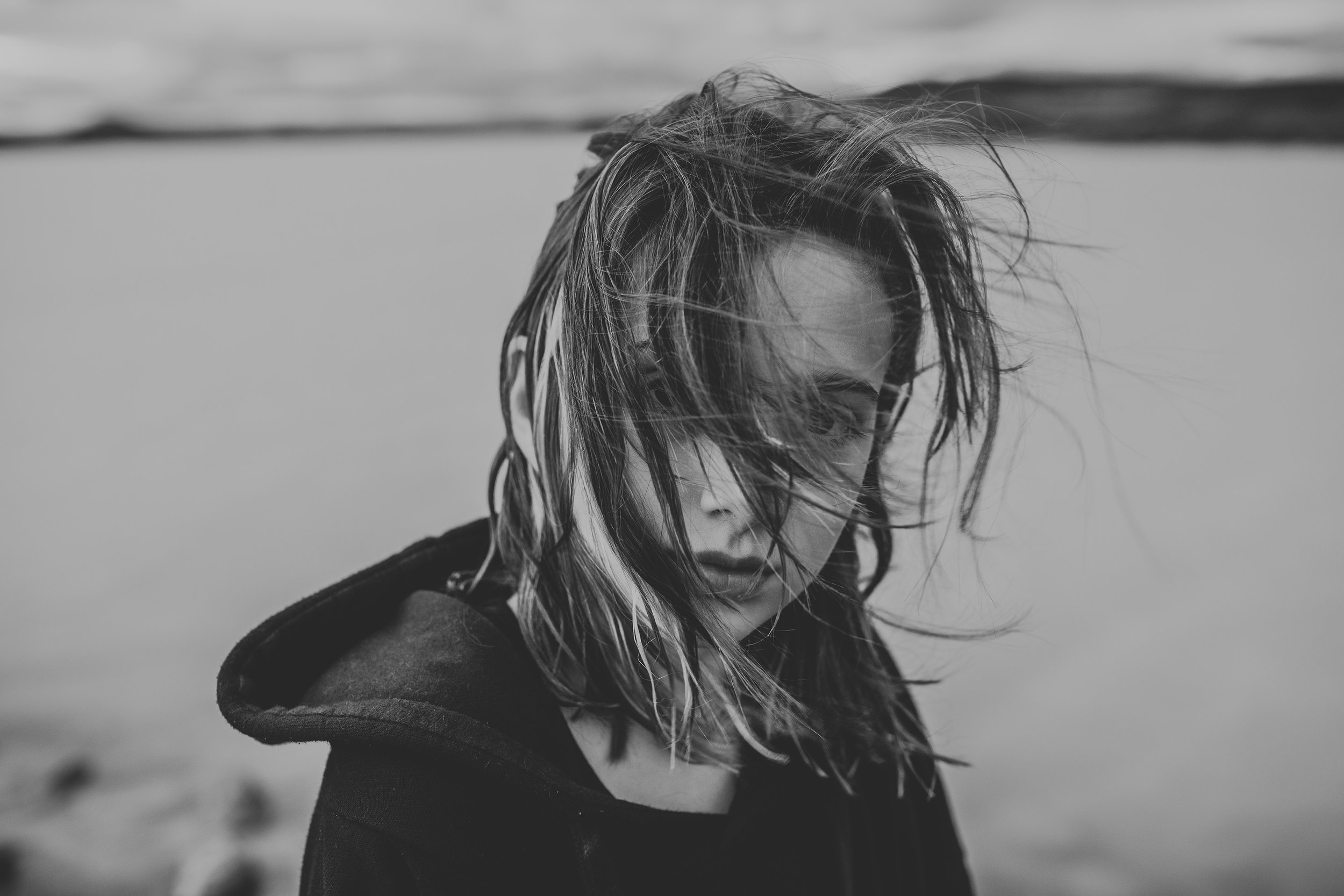A black-and-white close-up portrait of a child with wind-swept hair, evoking a sense of mystery and emotion.