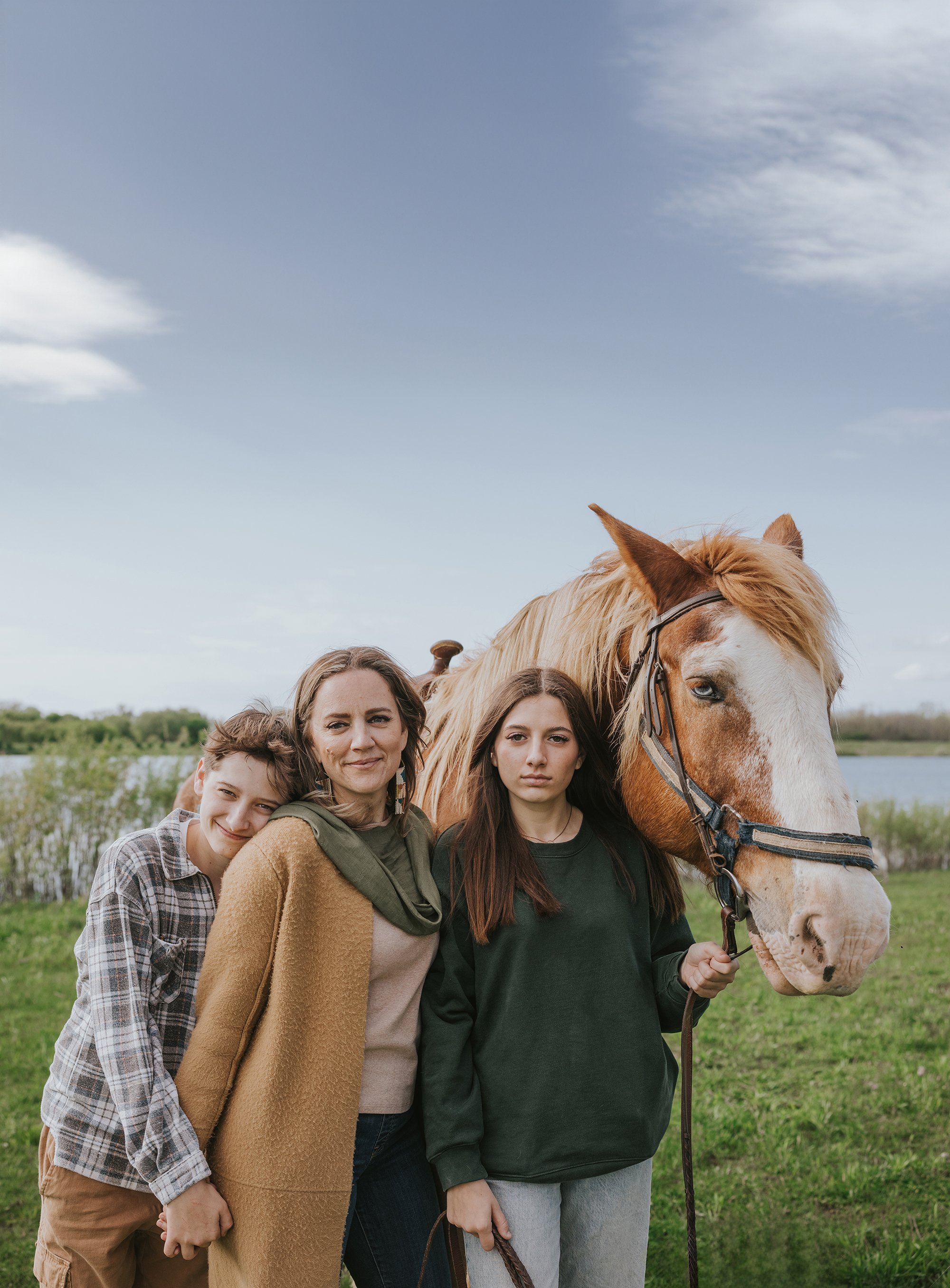 A family portrait in a natural setting with a large horse, showcasing a strong bond between the family members and their connection with nature.