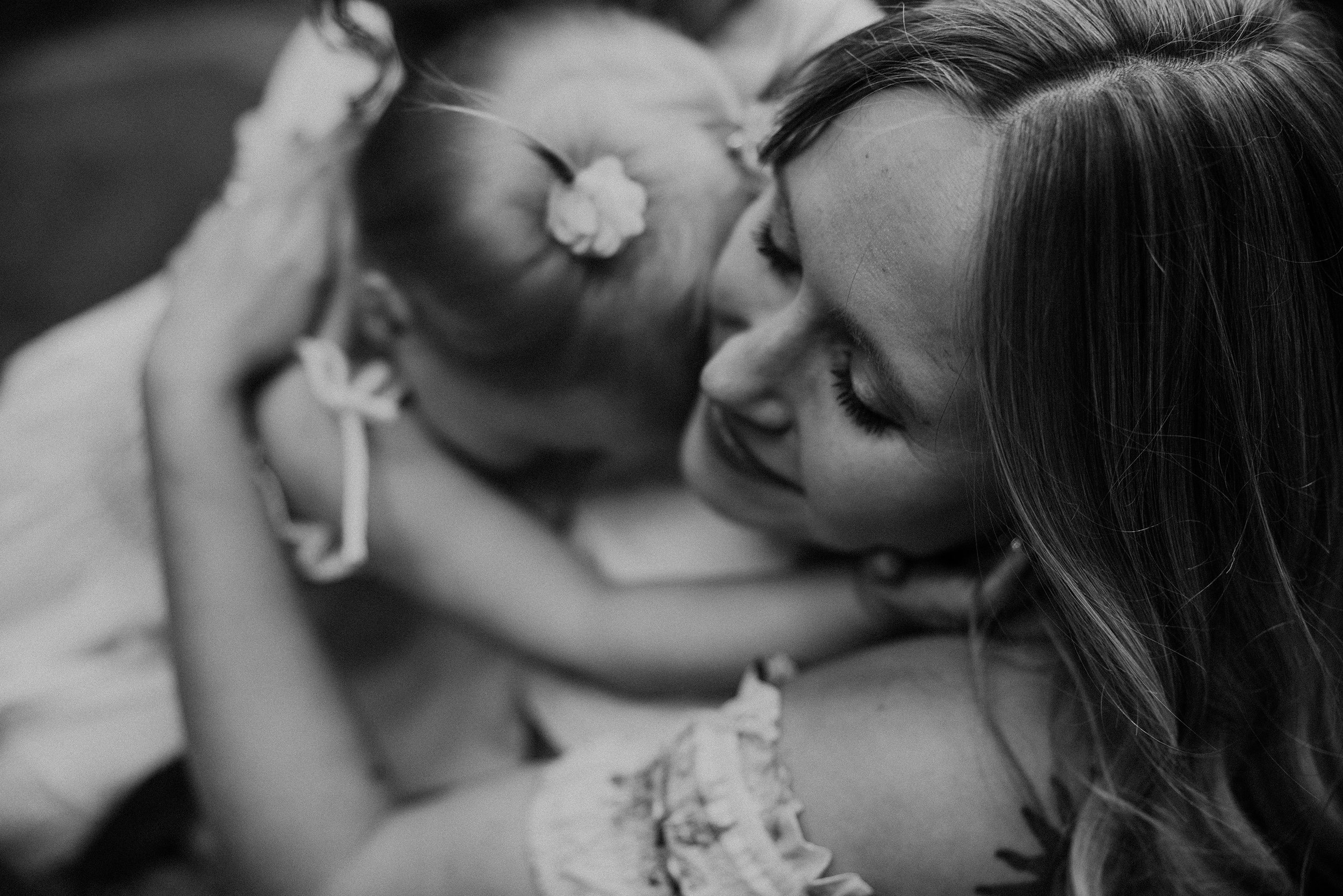 A close-up, black and white image of a mother and daughter hugging, capturing a tender bonding moment.