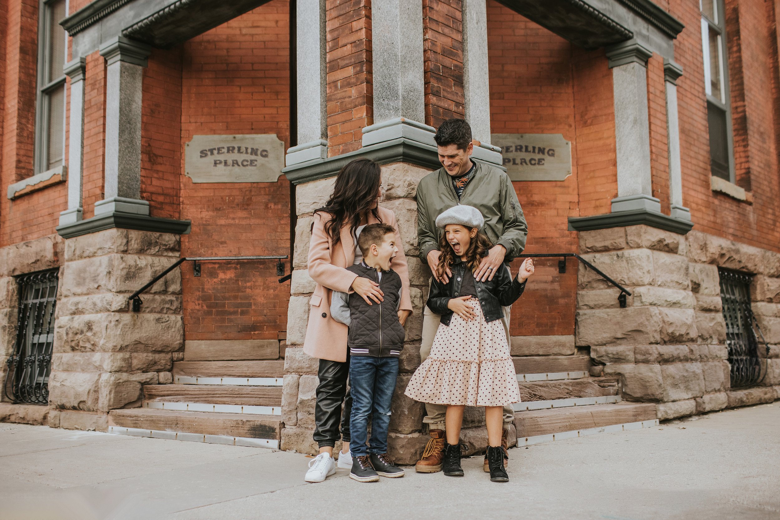 A family shares a joyful moment together on the corner of Sterling Place, with the parents and children laughing.