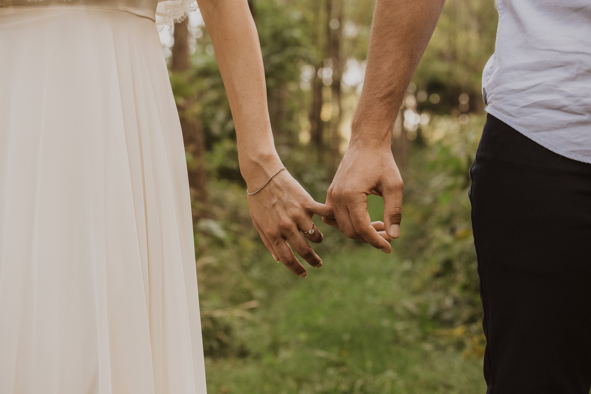 A close-up of a couple holding hands during a forest engagement session in London, Ontario.