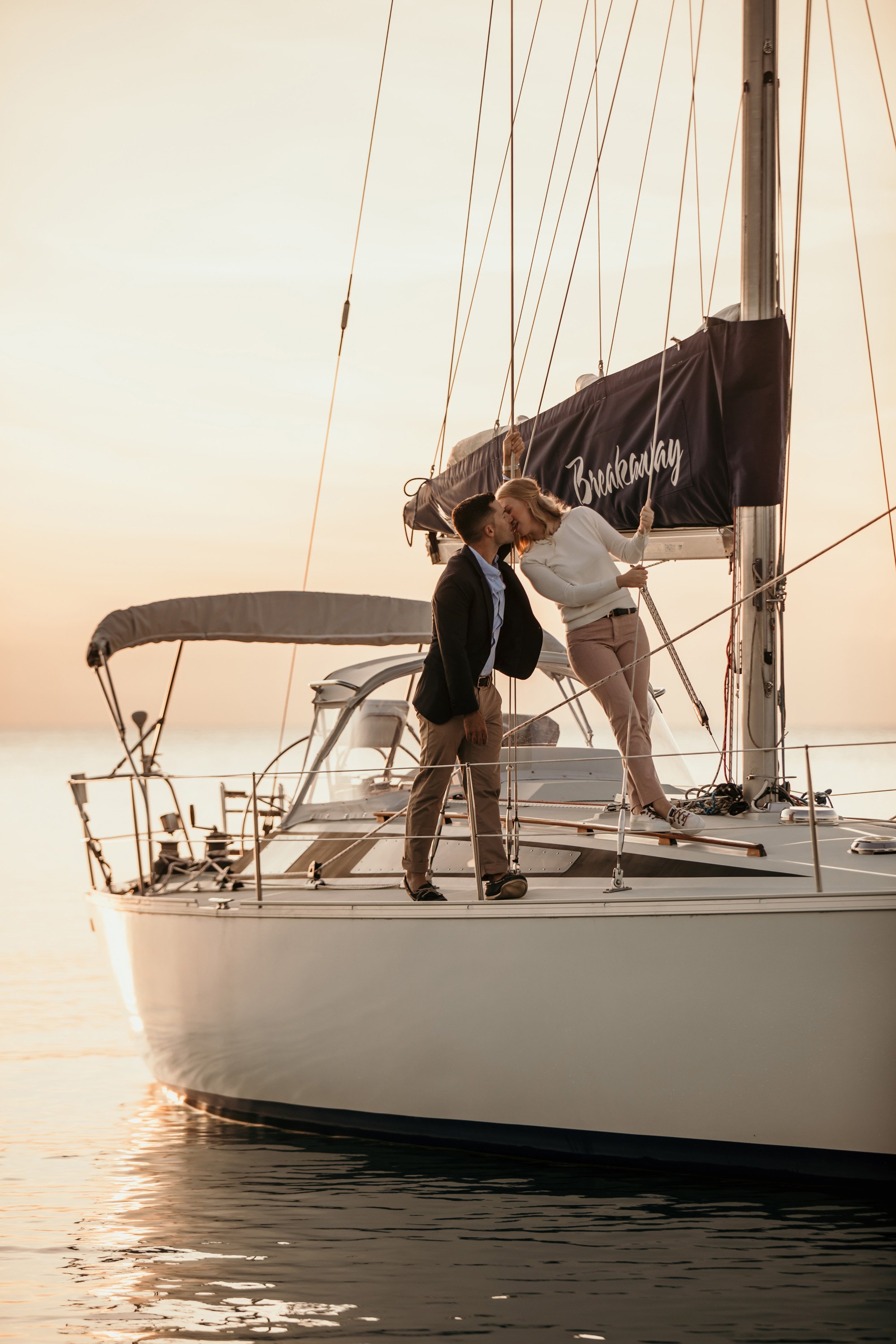A couple kisses aboard a luxury yacht during a sunset engagement session in Ontario.