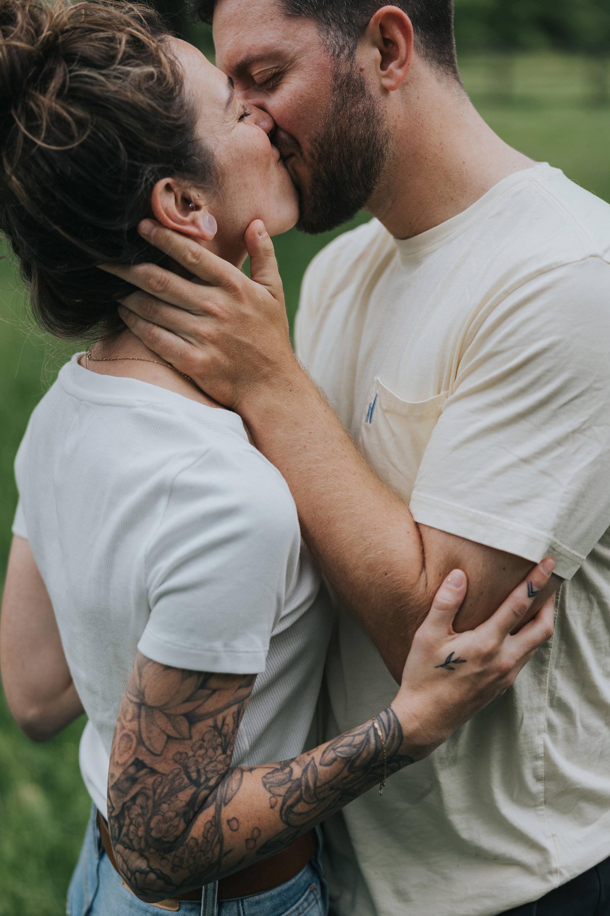 A close-up shot of a couple kissing, with the woman's tattooed arm adding a personal touch to the intimate moment.