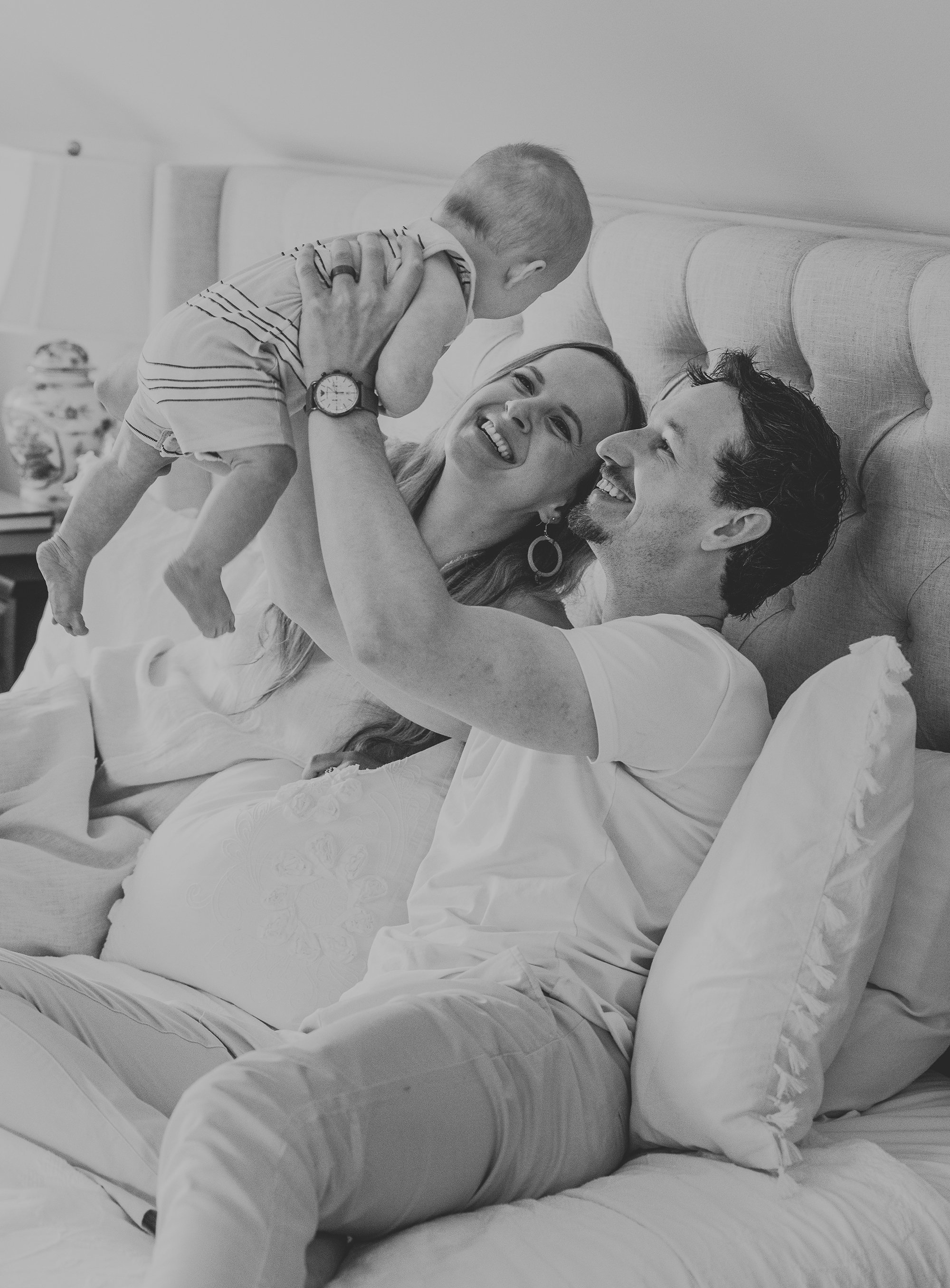 A joyful family playing with their baby on a bed, capturing a candid and happy moment at home.
