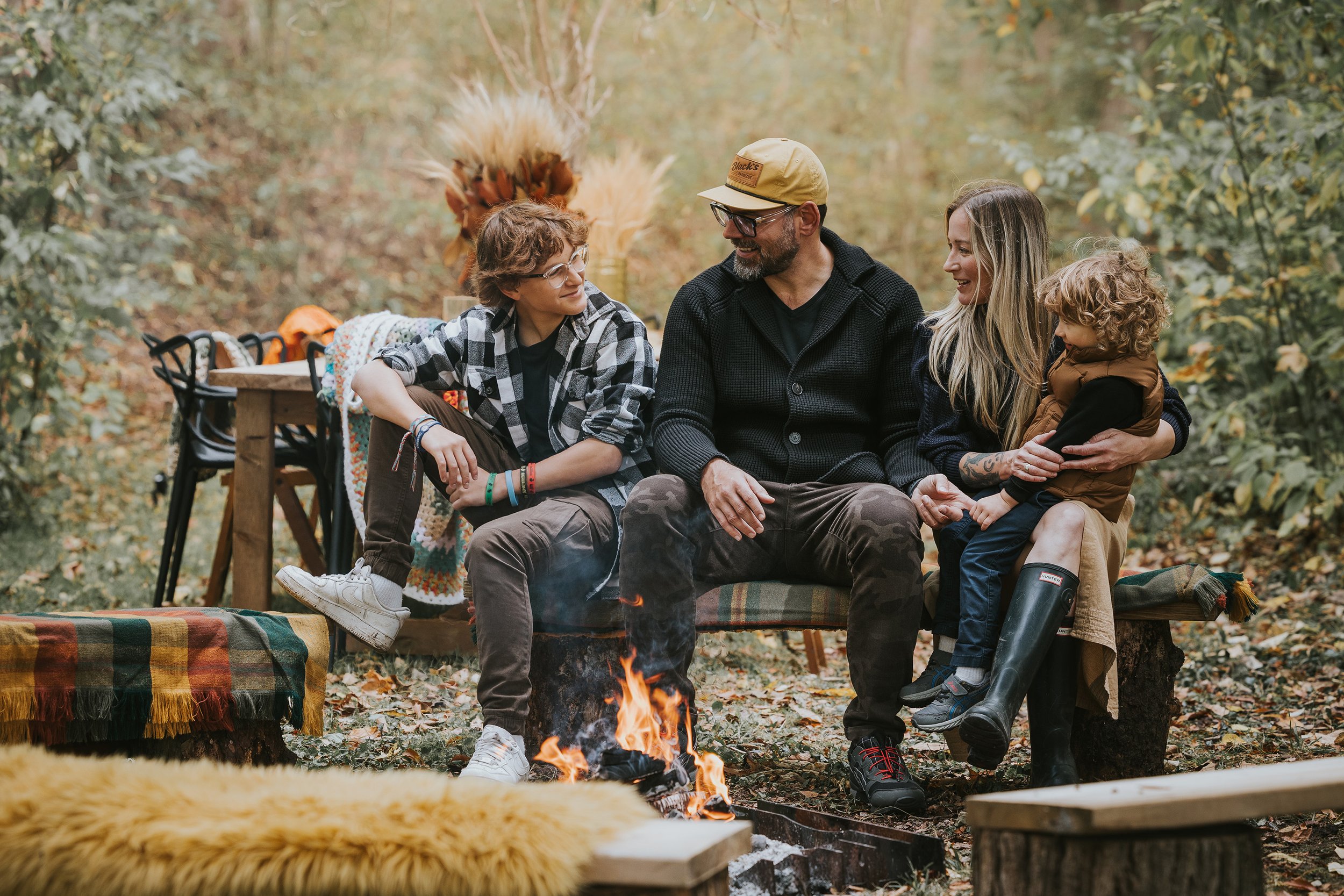 A family sitting around a bonfire in the autumn woods, enjoying a warm and cozy moment together.