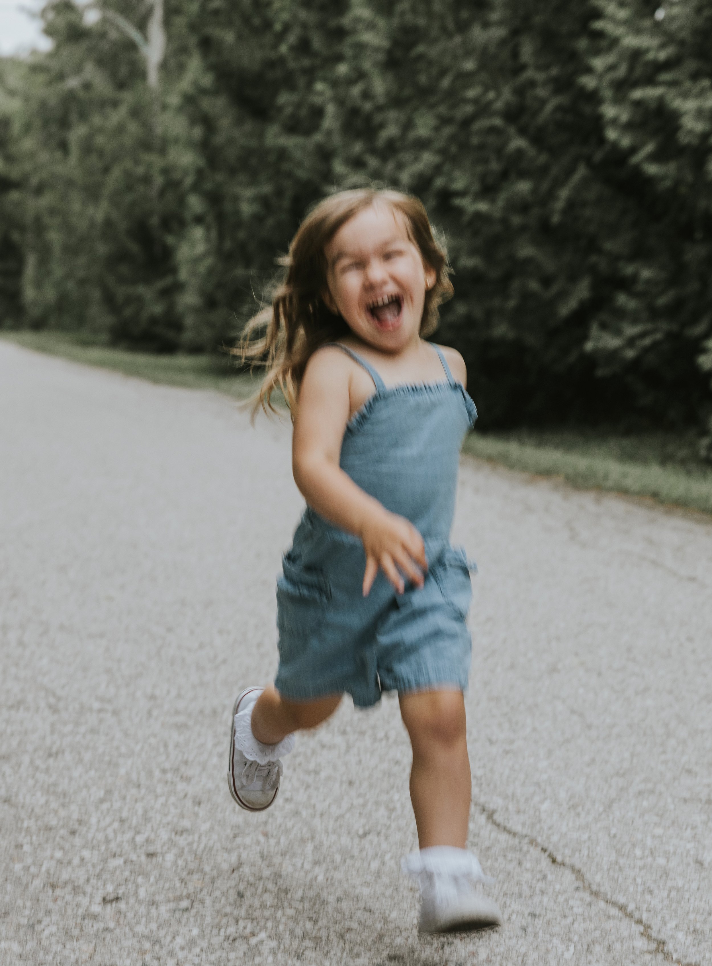 A joyful little girl running and laughing in a park in London, Ontario, capturing the fun and energy of the moment.