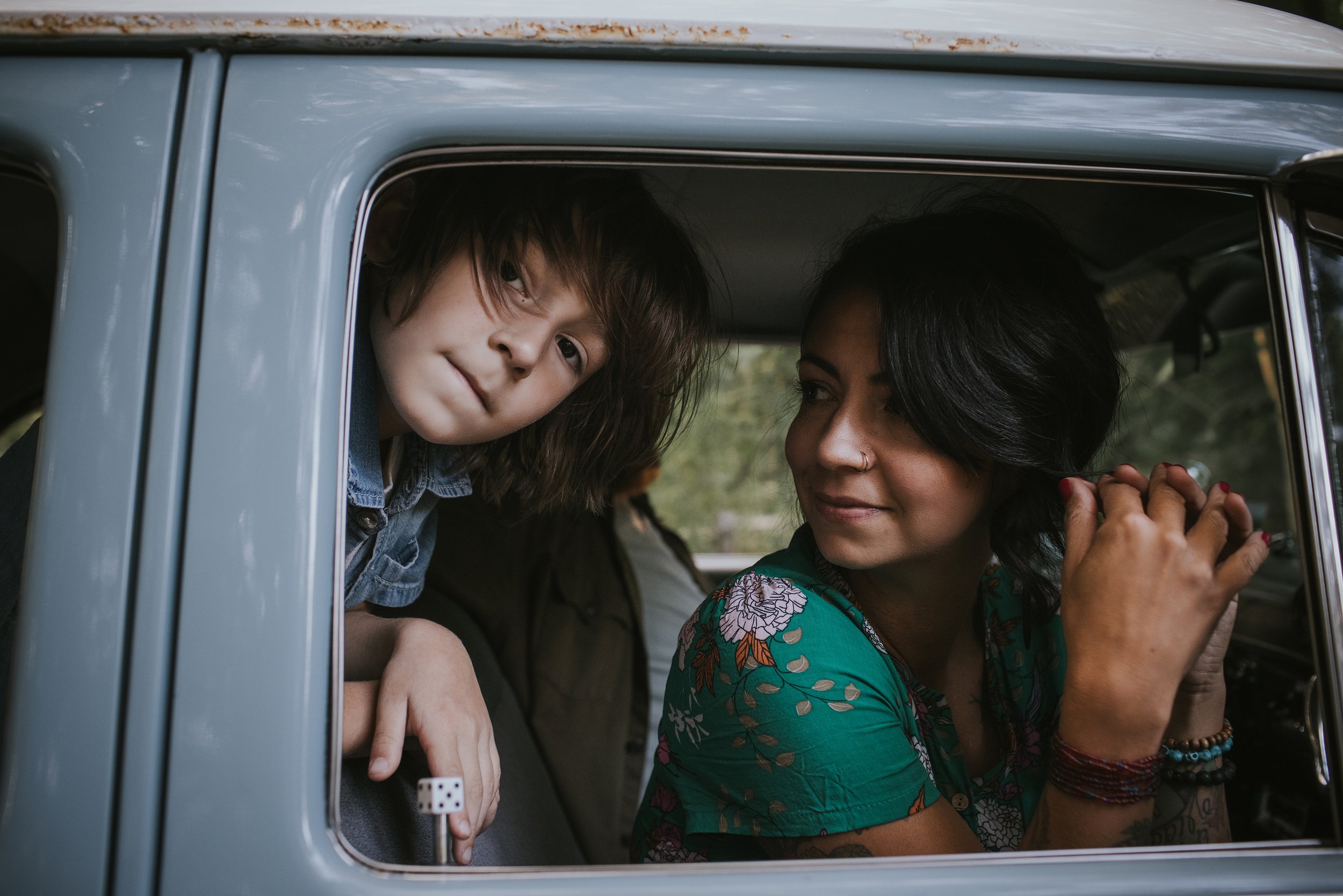 A candid moment of a mother and her son looking out of the window of a vintage car, capturing a nostalgic and intimate feel.