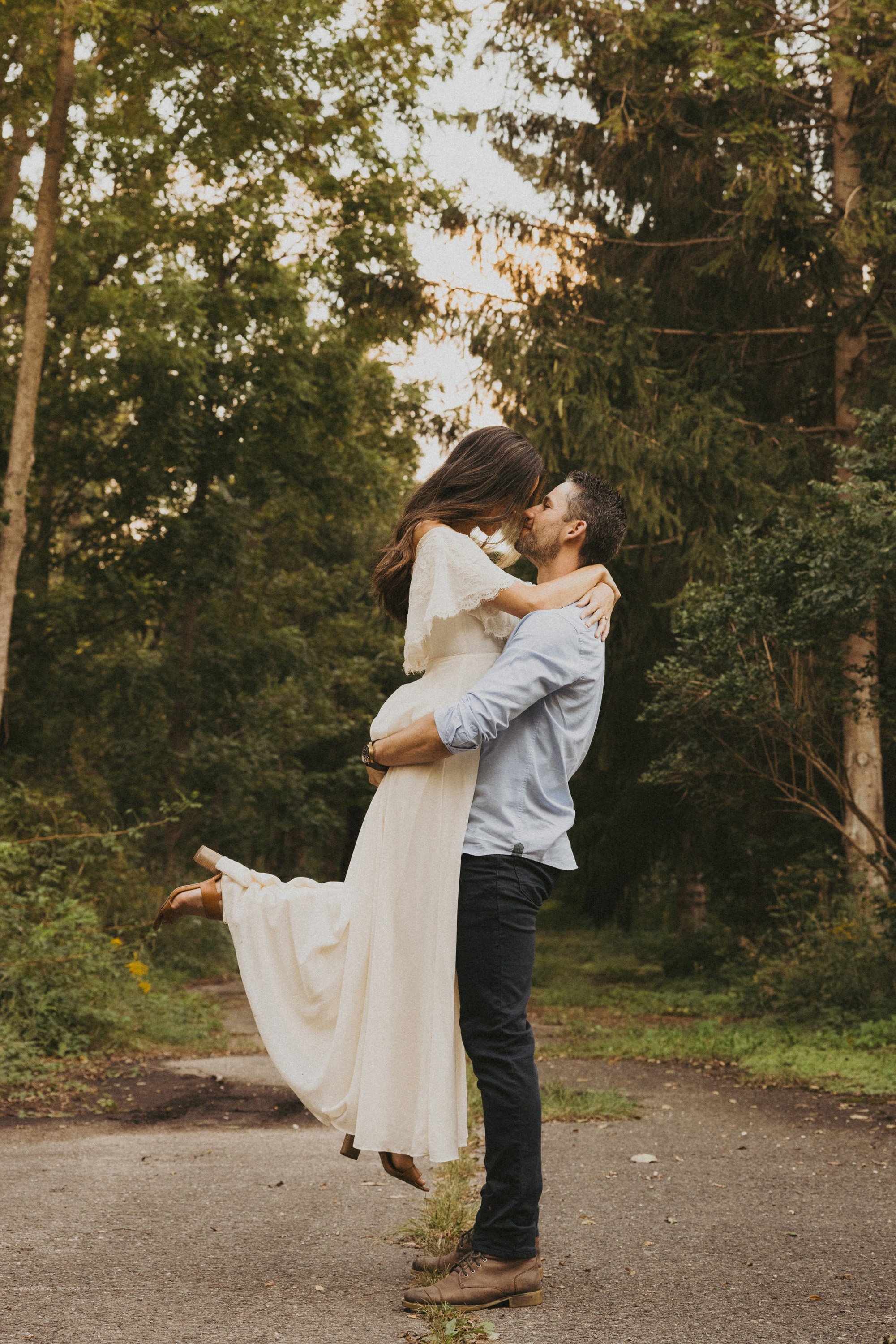 A couple sharing a loving embrace in a forest setting, with the trees providing a natural, serene backdrop.