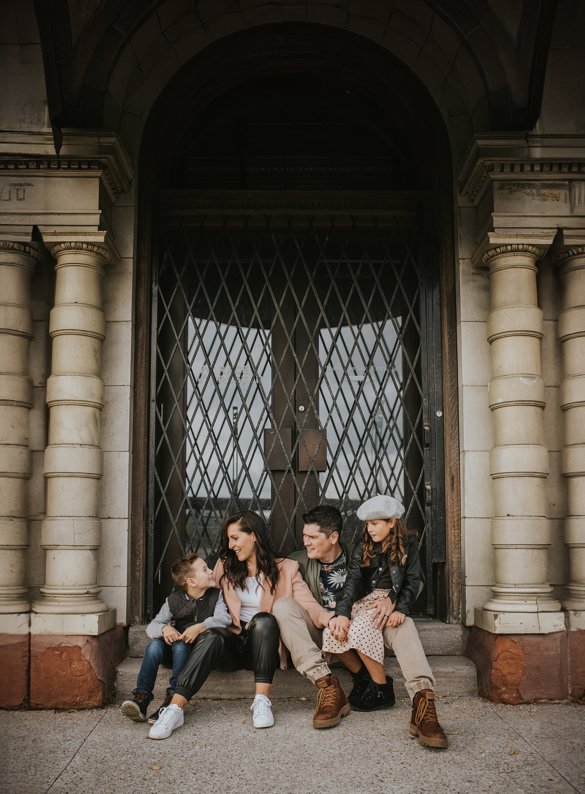 A family sits on the steps of an urban building, sharing a moment of laughter and connection.