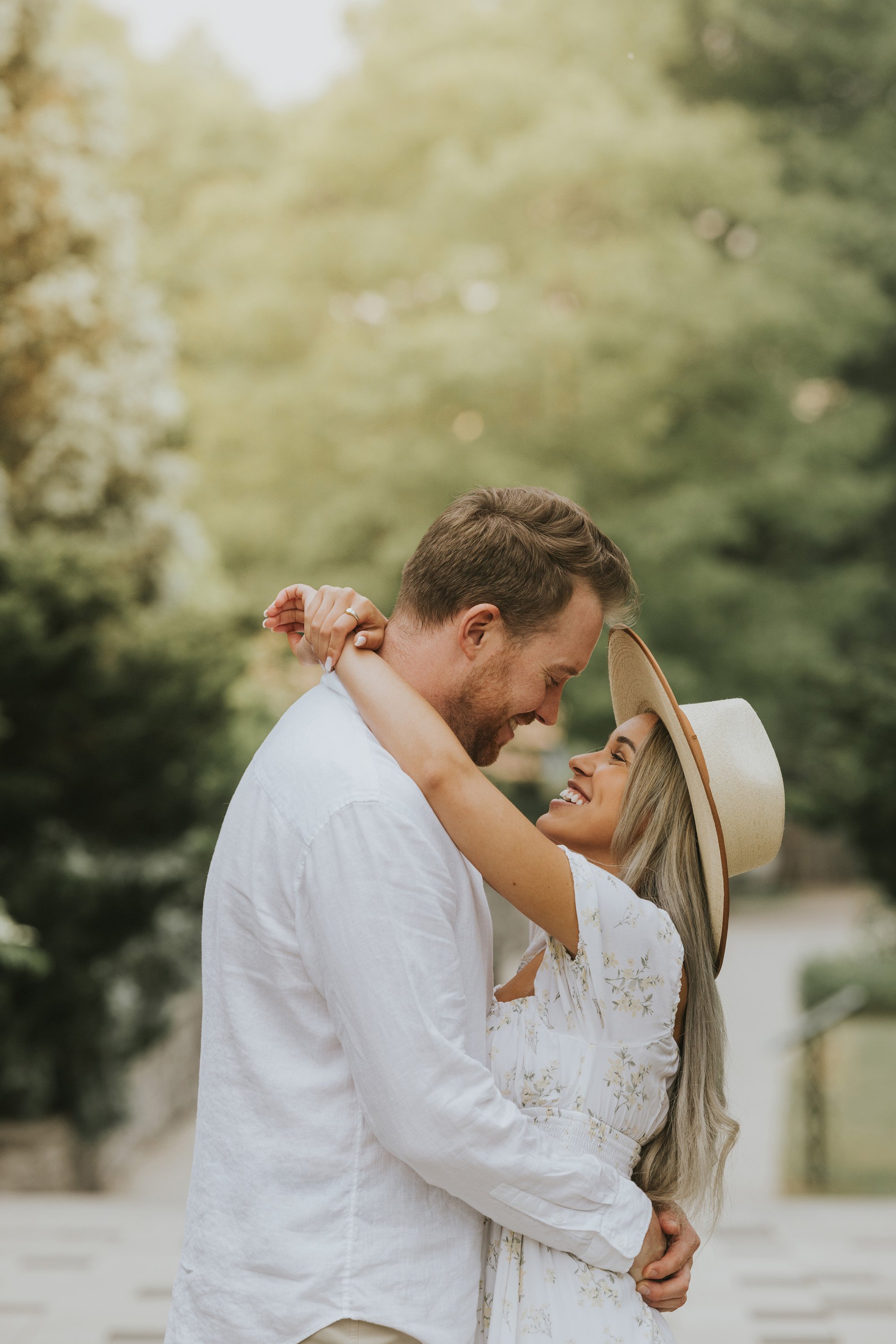 A couple shares an intimate moment, gazing into each other's eyes while standing close together in a lush garden.
