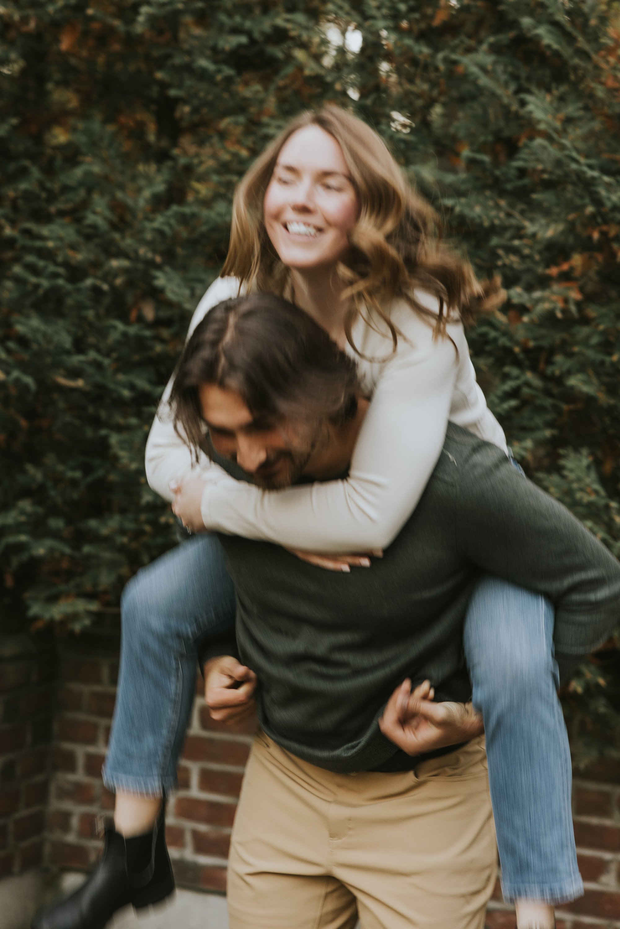 A playful moment captured as a couple laughs together during a piggyback ride.