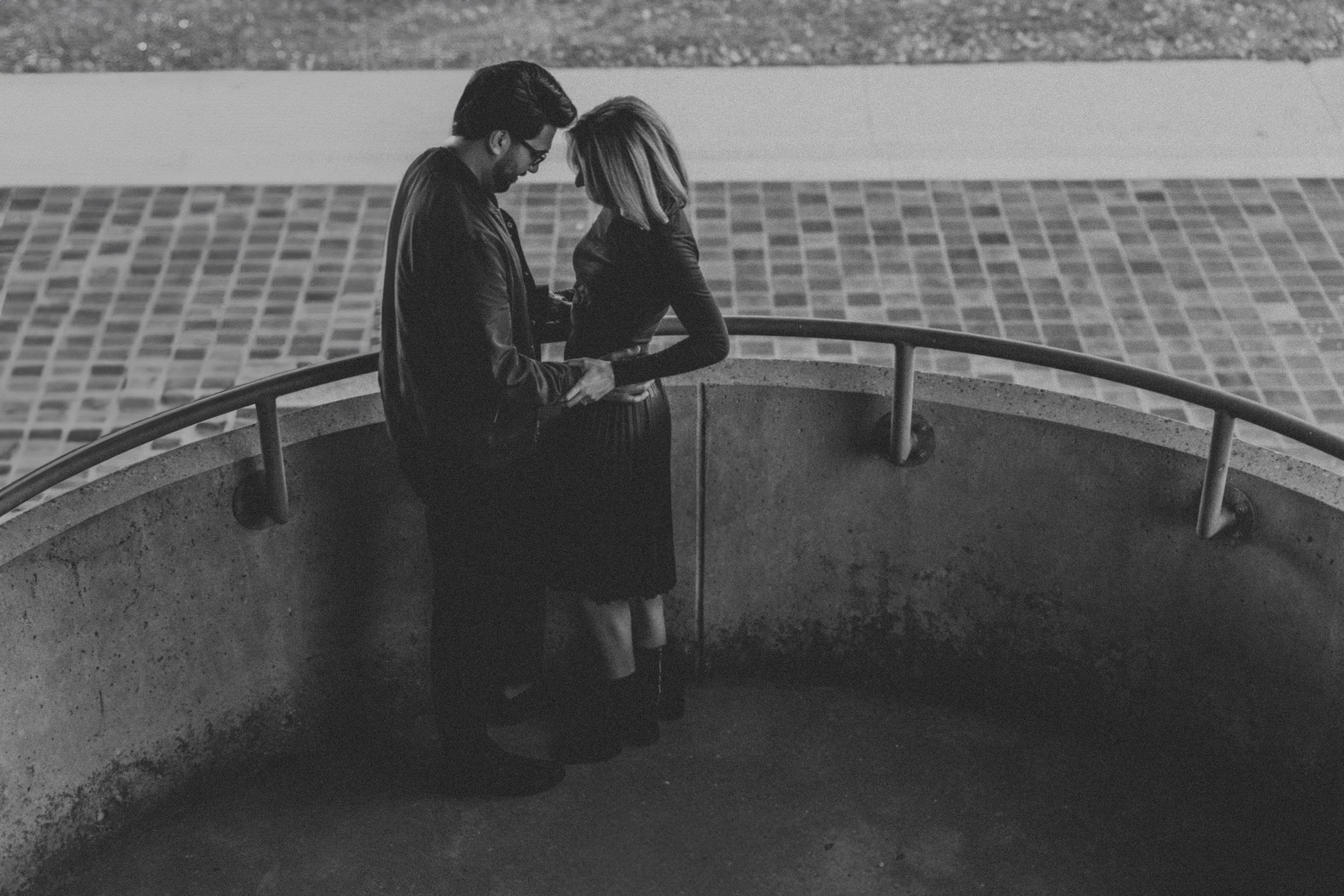 A moody black-and-white photograph of a couple embracing during their engagement session.
