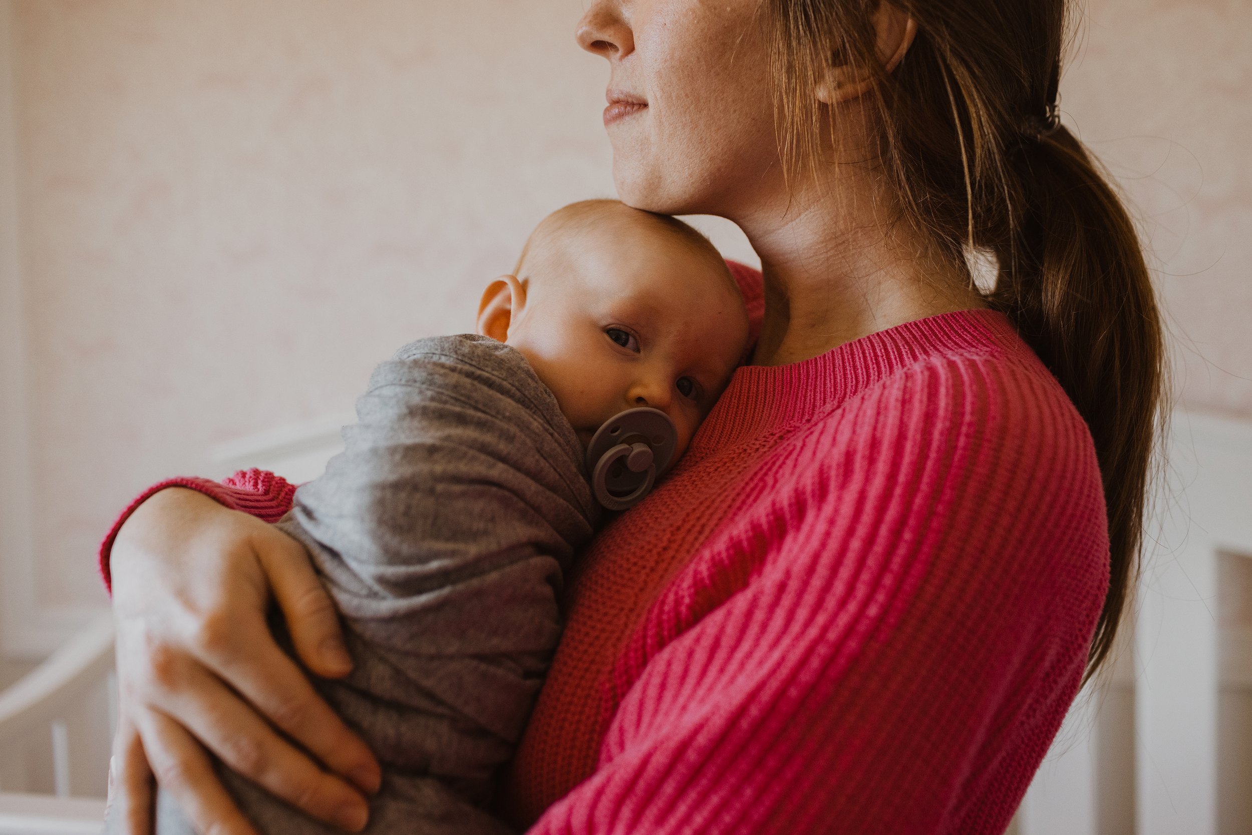 A mother holding her baby in a soft, natural light, creating a warm and intimate scene.