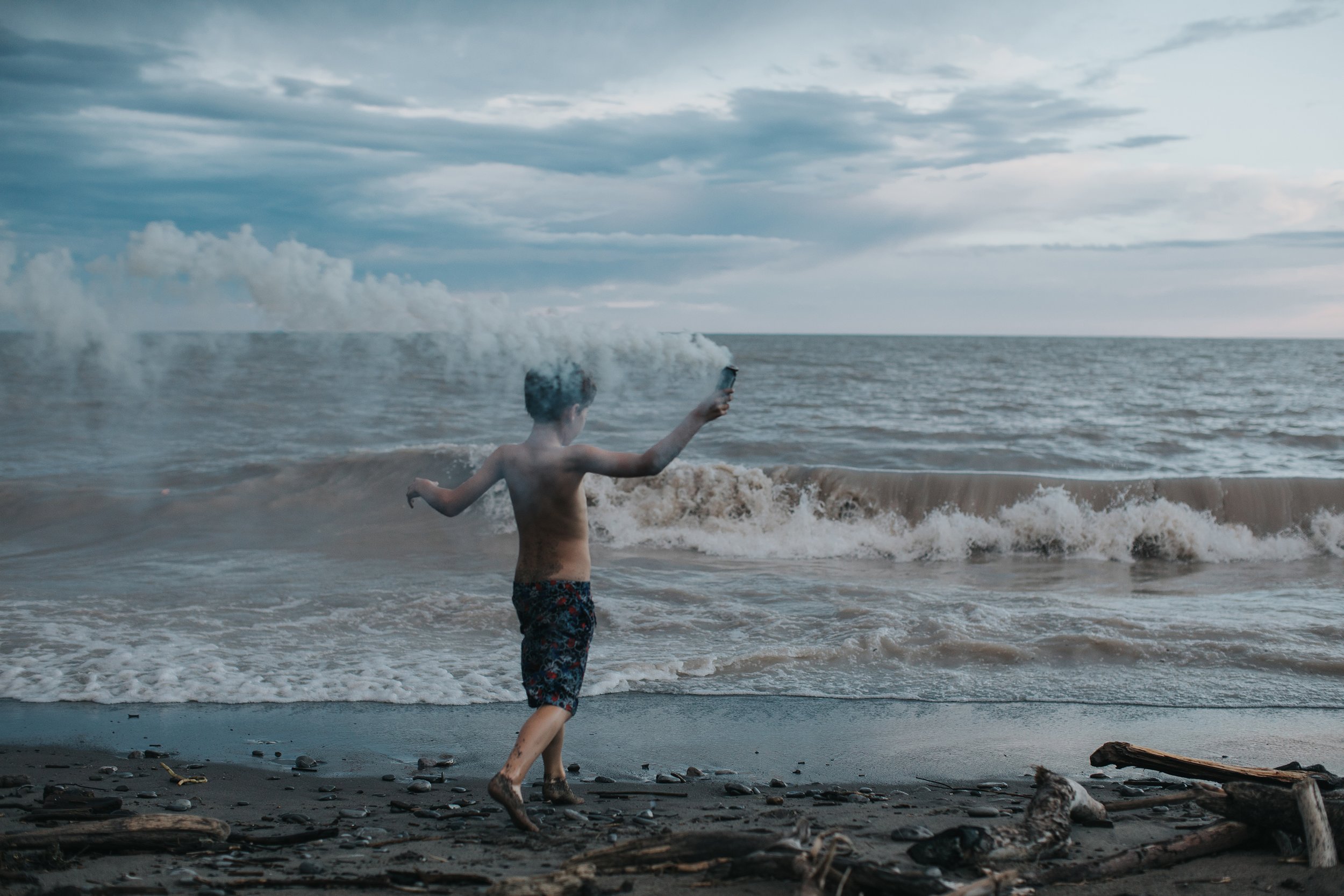 A child running along a beach with smoke in the air, creating an adventurous and atmospheric scene.