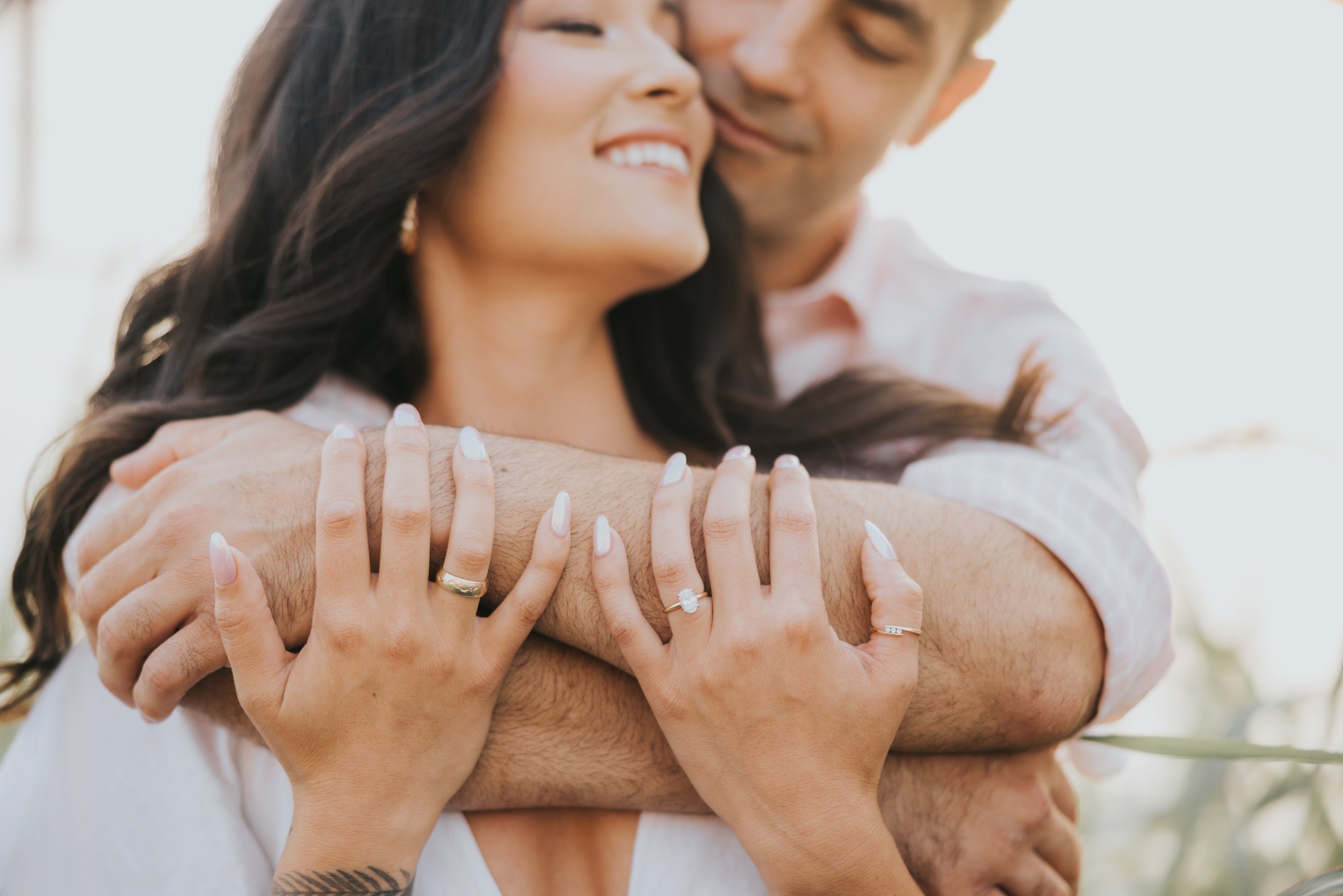 A close-up shot of an engaged couple embracing, showcasing the engagement ring and their intertwined hands, symbolizing their love and commitment.