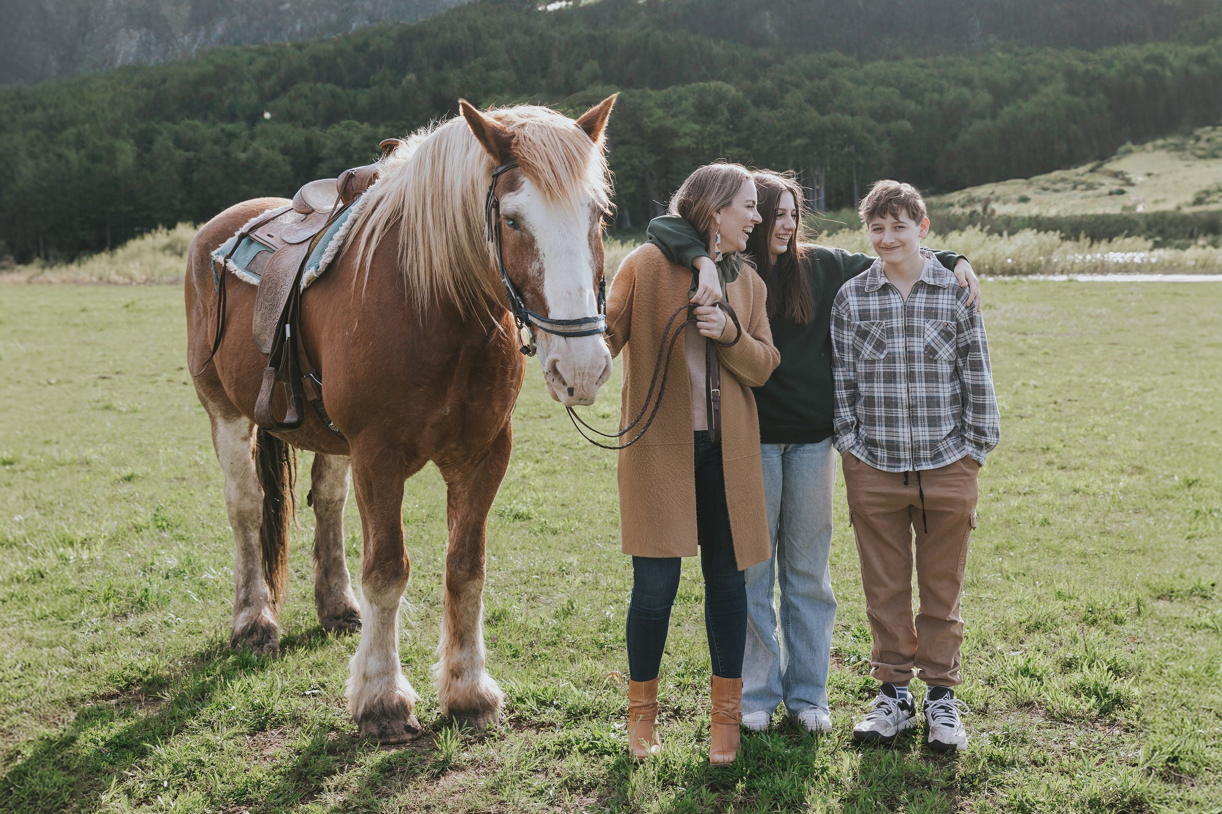 A family standing together with a horse in a picturesque nature setting, highlighting their bond with each other and the animal.