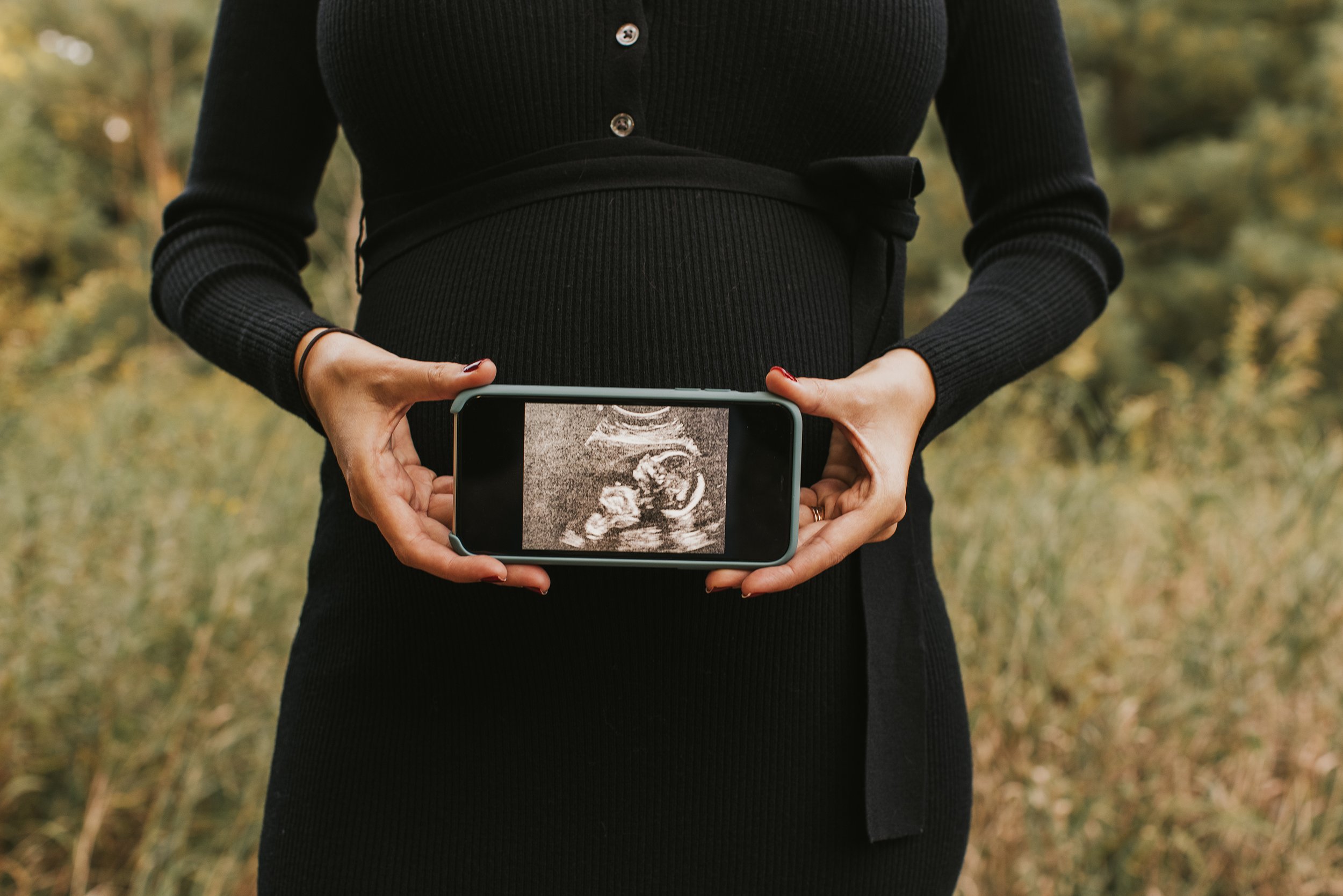 A close-up of a pregnant woman holding an ultrasound photo over her belly, capturing a special moment of anticipation.